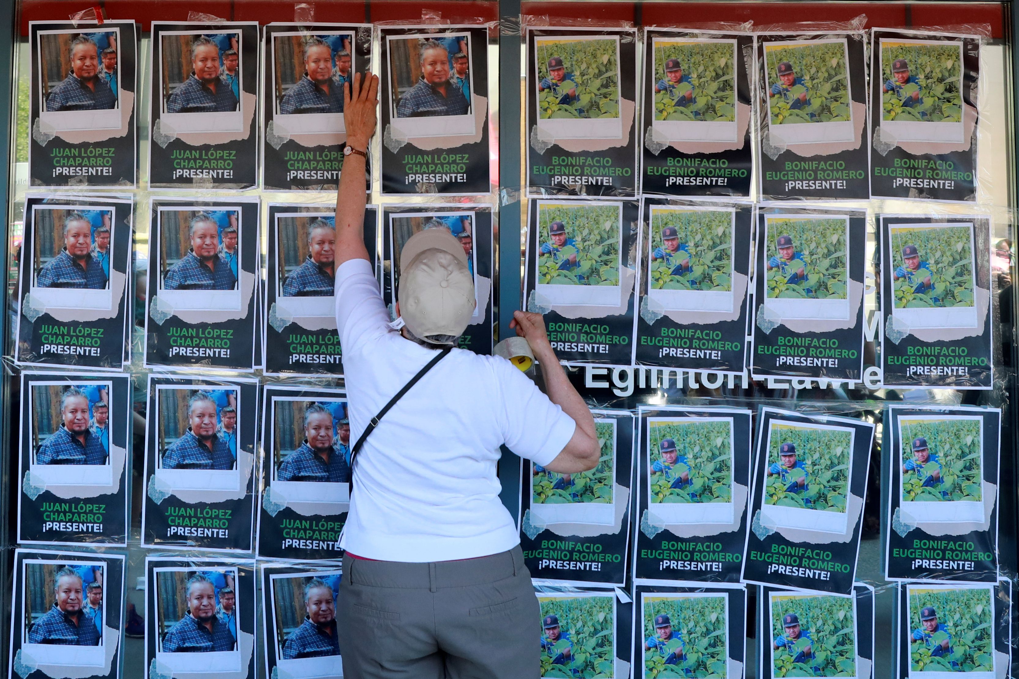 Supporters tape photos of migrant workers who died from COVID-19 while working in Canada