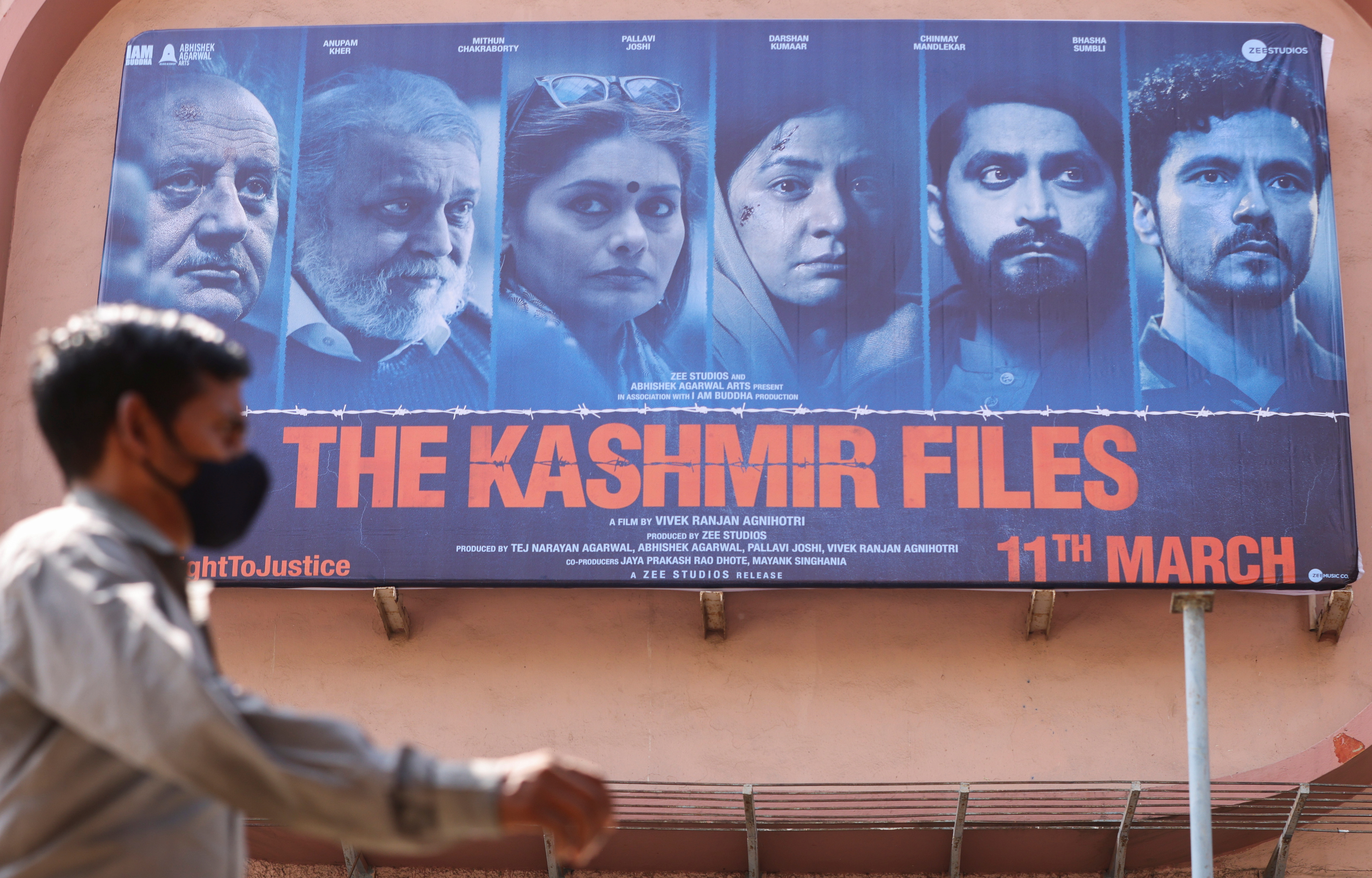 A man walks past a poster of Bollywood movie "The Kashmir Files" outside a cinema in Mumbai, India, March 16, 2022.