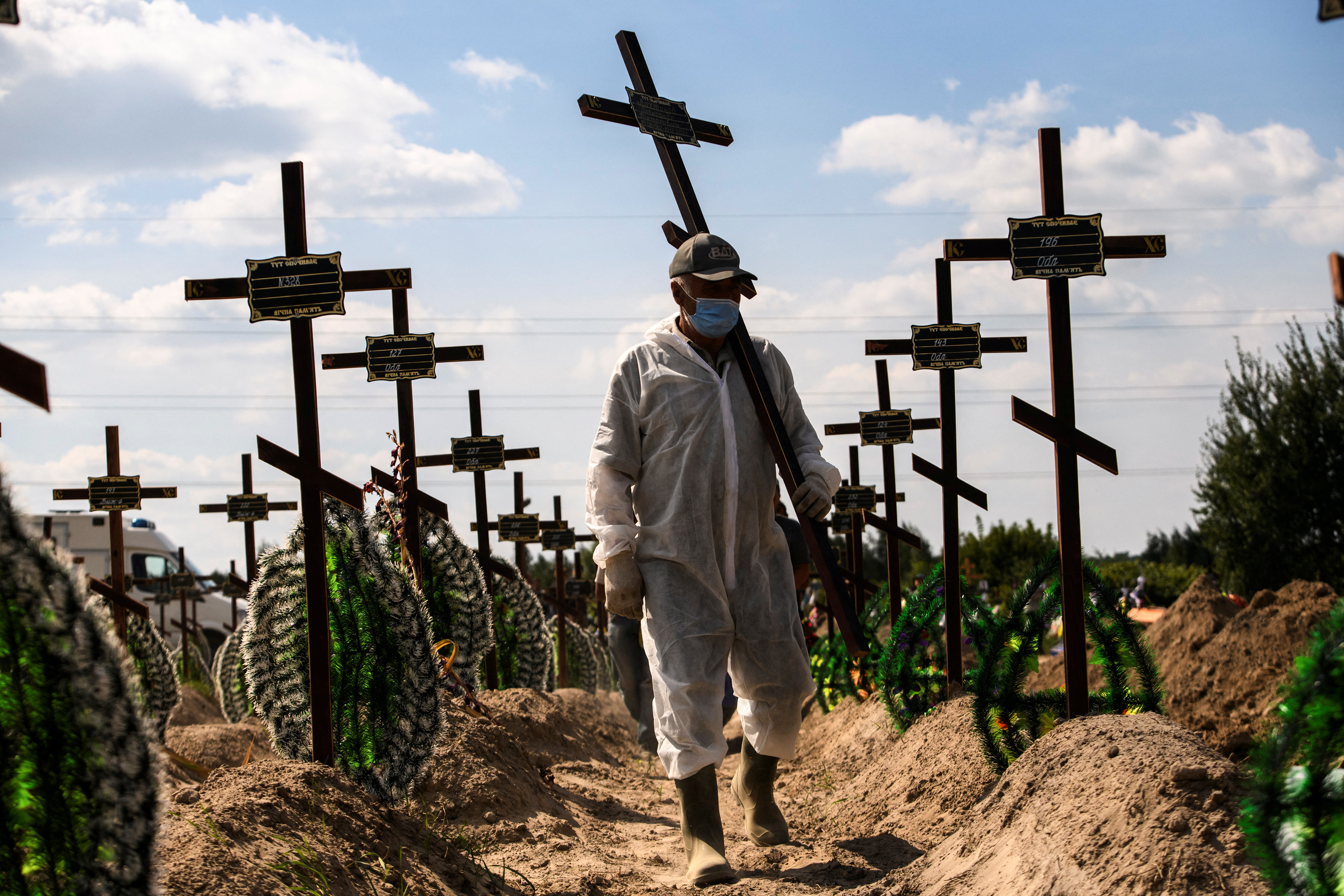 A volunteer places a cross with a number to a grave of one of unidentified people killed by Russian troops, as Russia's attack on Ukraine continues, during a mass burial ceremony in the town of Bucha, in Kyiv region, Ukraine September 2, 2022. REUTERS/Vladyslav Musiienko