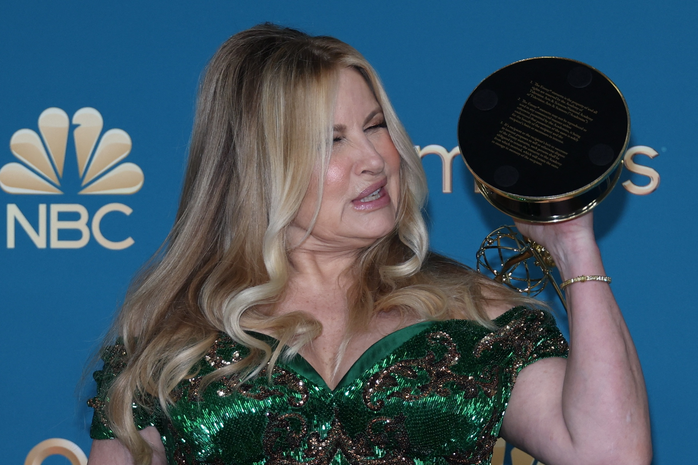 Jennifer Coolidge, in a dark green dress, holds her Emmy