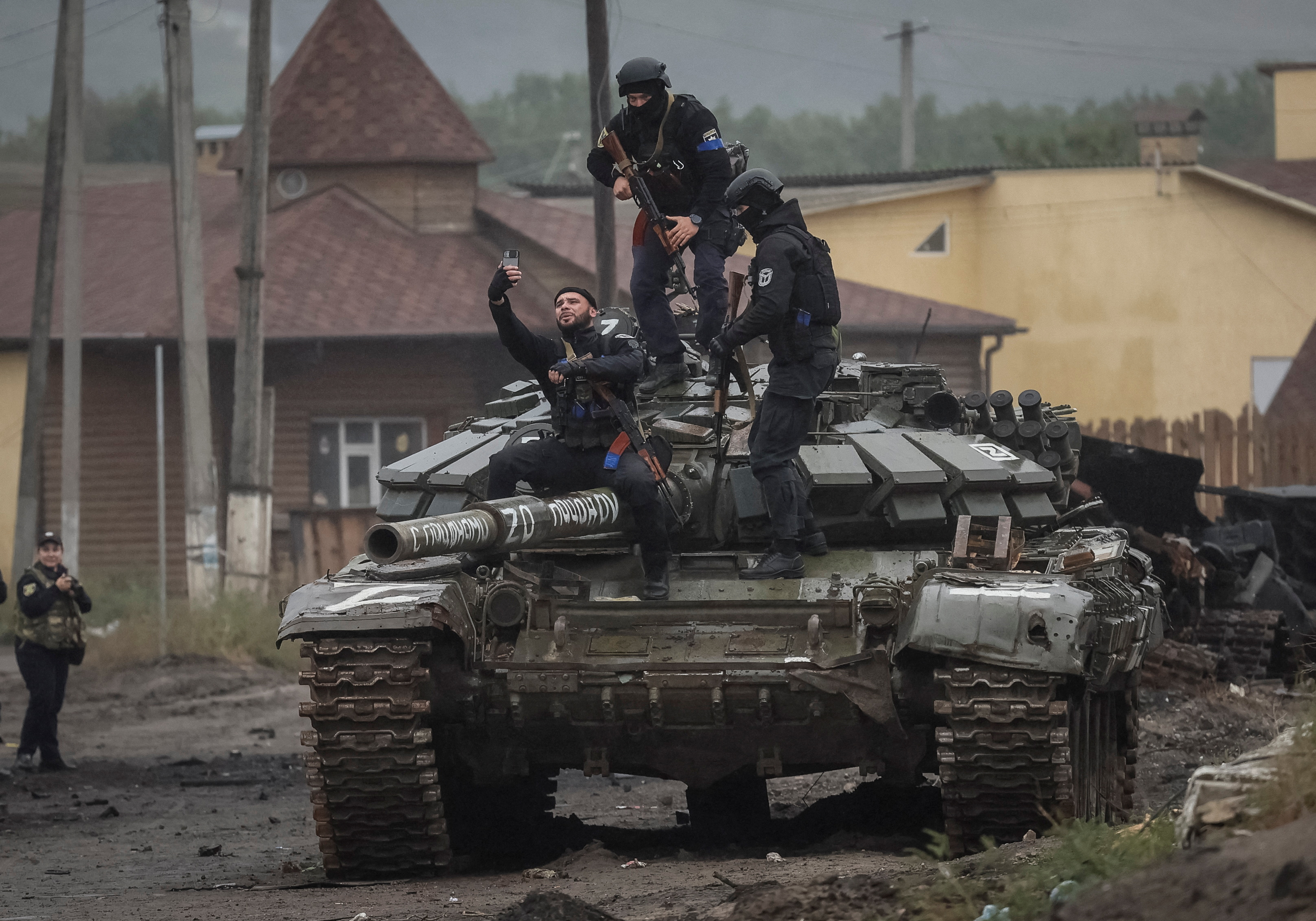 Police officers take a selfie on a destroyed Russian tank, as Russia's attack on Ukraine continues, in the town of Izium, recently liberated by Ukrainian Armed Forces, in Kharkiv region, Ukraine September 14, 2022. REUTERS/Gleb Garanich