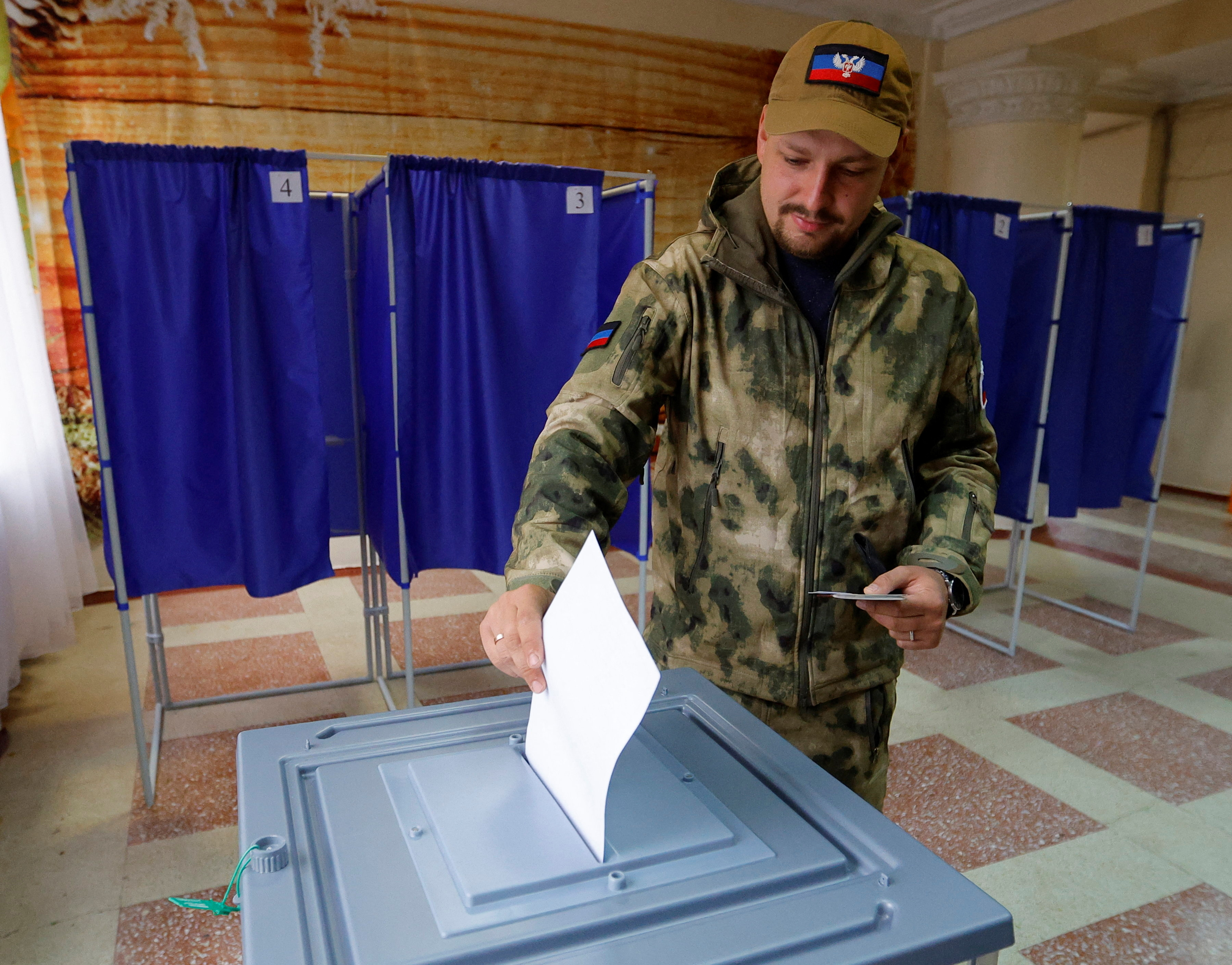 A service member of the self-proclaimed Donetsk People's Republic (DPR) casts his ballot at a polling station during a referendum on the joining of DPR to Russia
