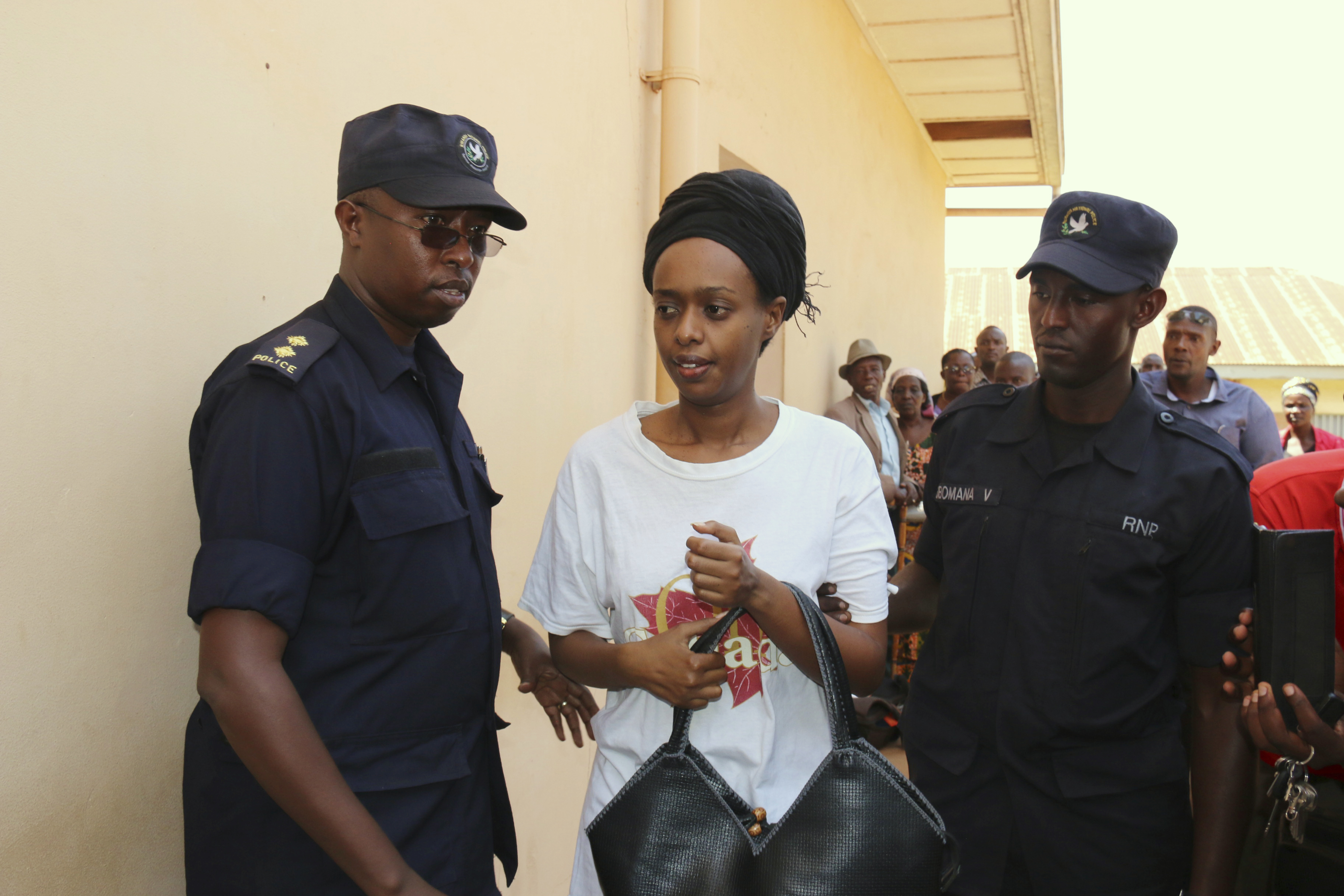 FILE - In this Friday, Oct. 6, 2017 file photo, former Rwanda presidential candidate Diane Rwigara is escorted by policemen to a court where she denied charges of insurrection and forgery that she says are linked to her criticism of the government's human rights record. As she waits for a judge to pronounce her fate on Thursday, Dec. 6, 2018, the Rwandan opposition leader accused of inciting insurrection and forgery says no amount of pressure will silence her. (AP Photo, File)