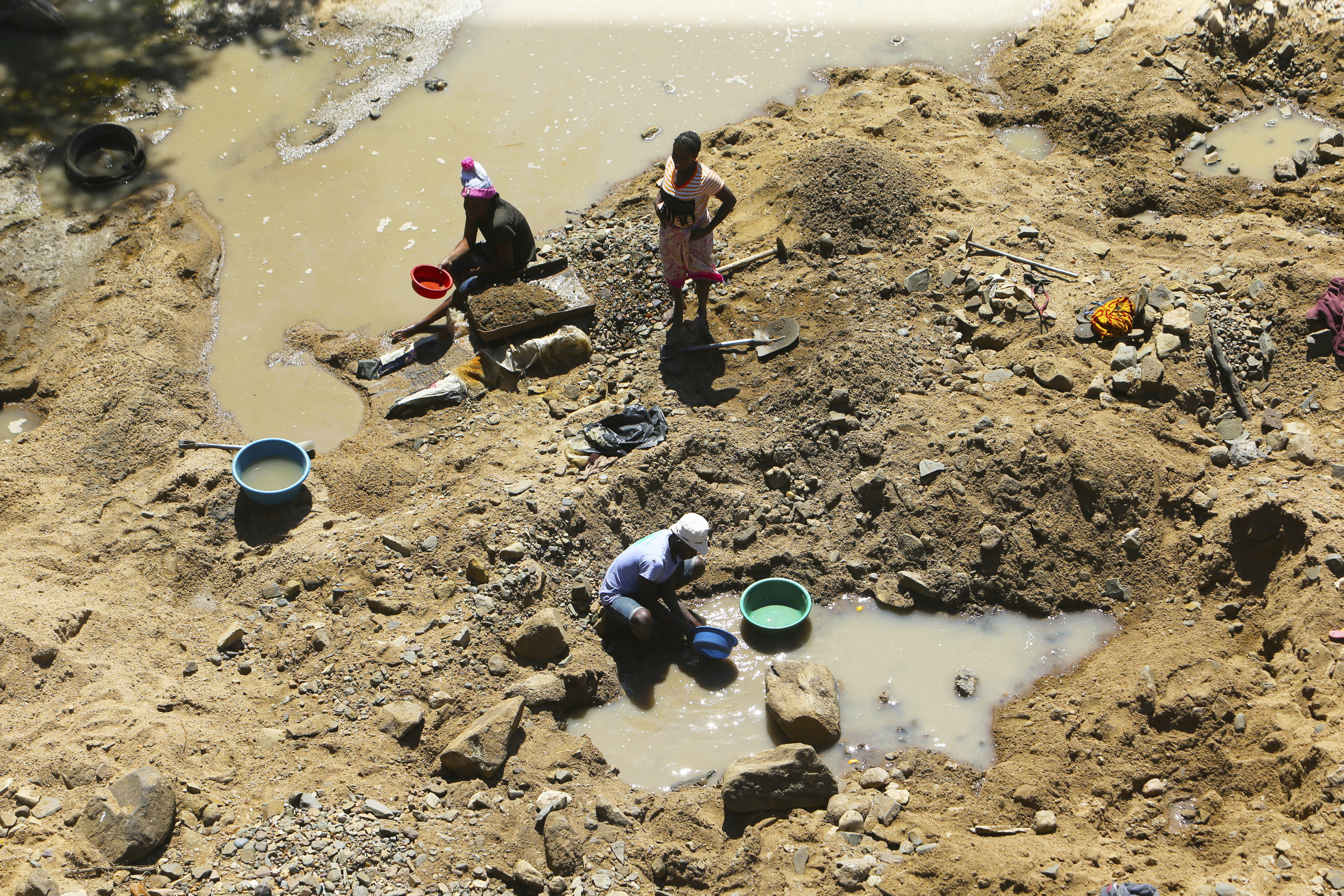 Small scale miners on a river bed on the outskirts of Harare, Wednesday, Sept. 9, 2020. Zimbabwe’s government says it has banned mining in its national parks, but an environmental group that had taken court action to stop the development of a coal mine in an elephant-rich park said on Wednesday that it will insist on “more than just words.” (AP Photo/Tsvangirayi Mukwazhi)