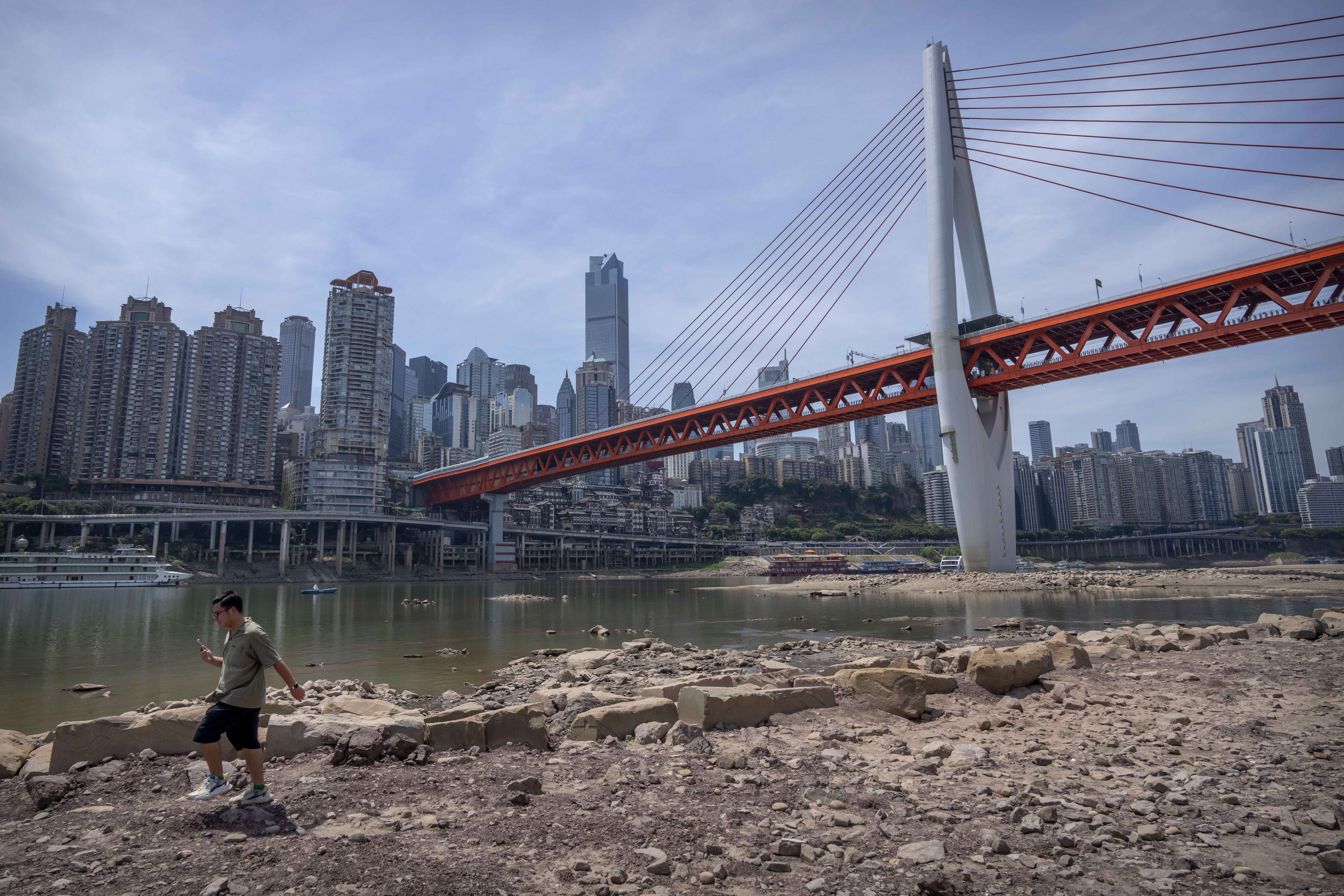 A man walks along the lower than normal bank of the Jialing River in southwestern China's Chongqing Municipality.