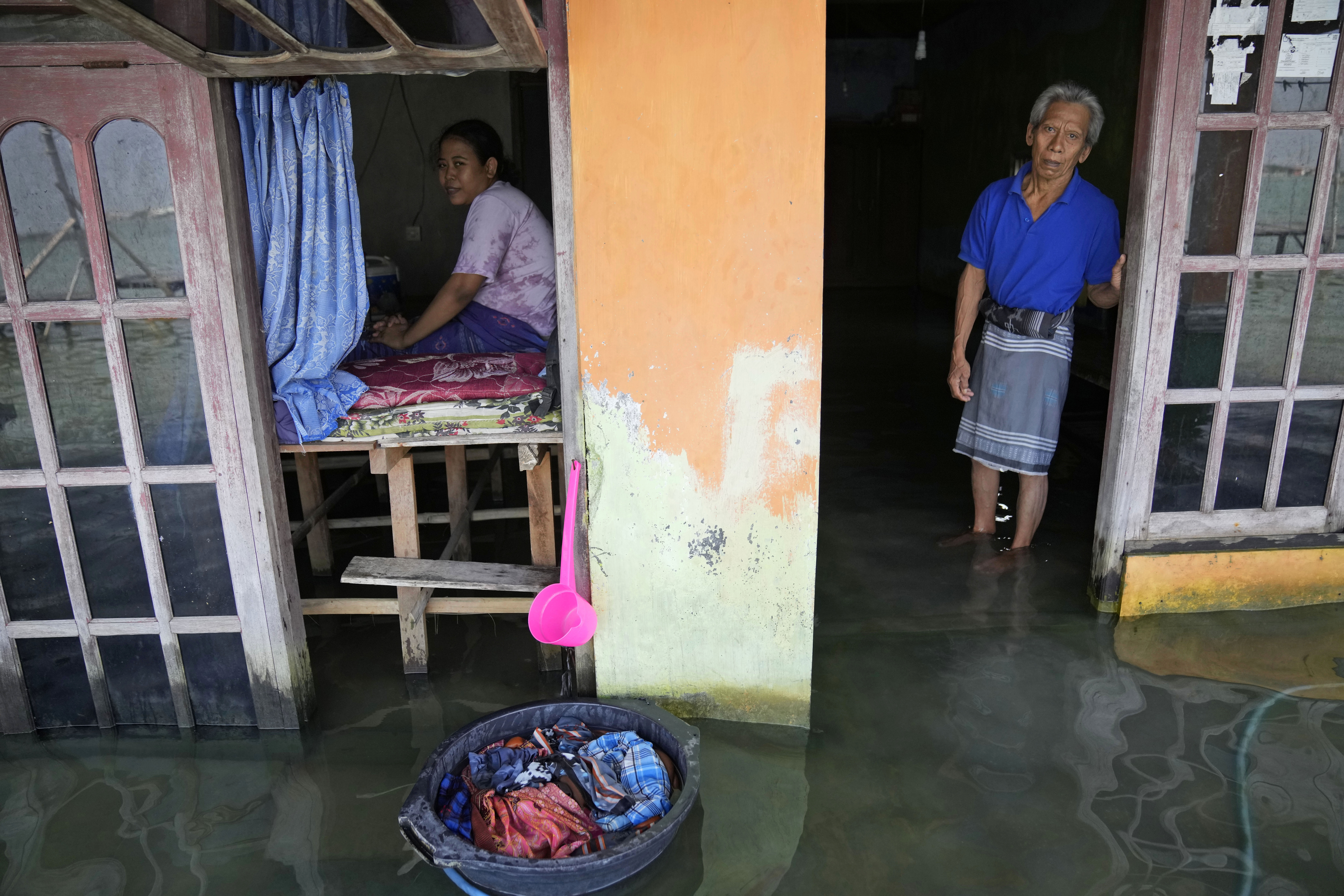 Sudarto stands at the door of his flooded home