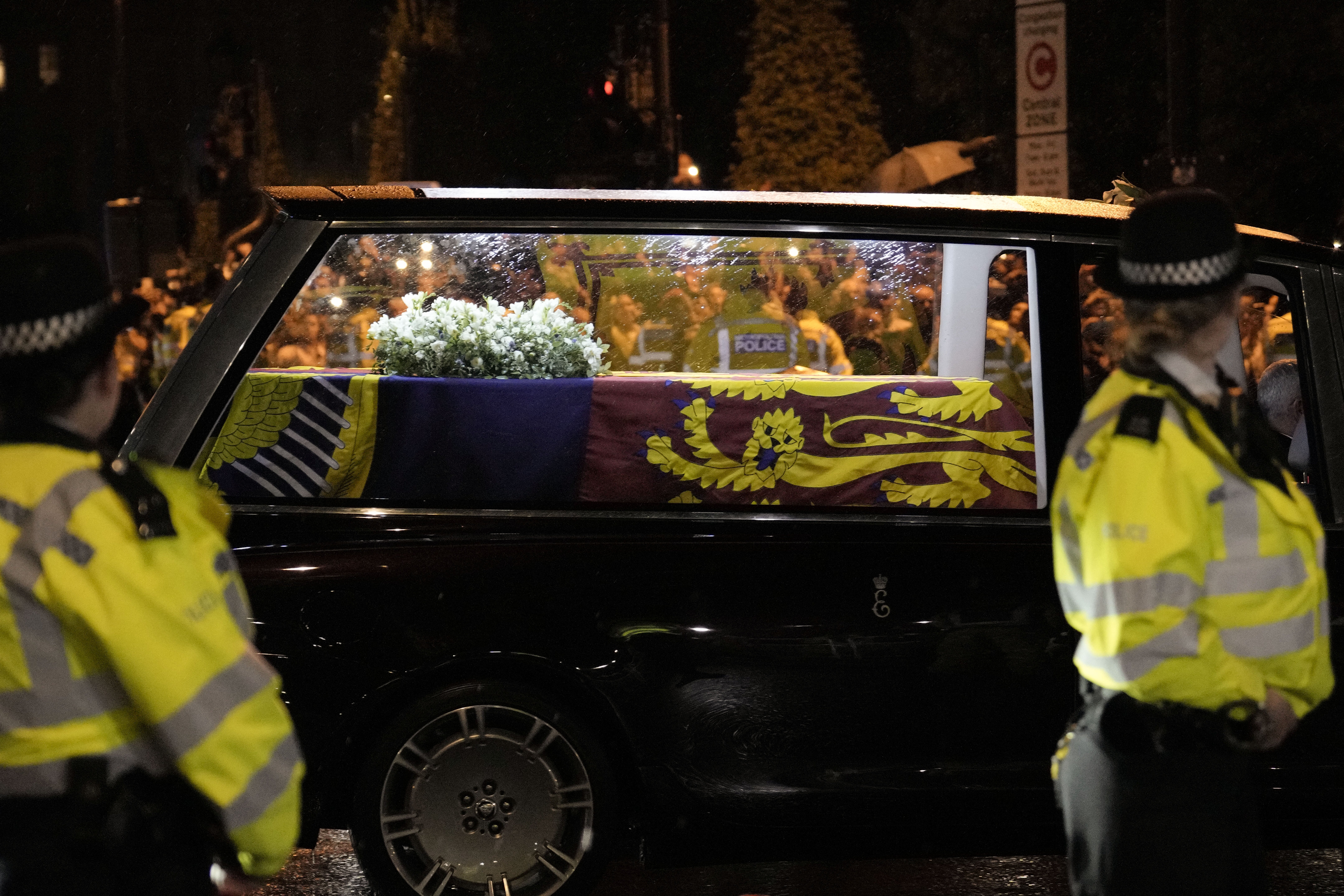 The queen's flag-draped coffin passes through a crowd-lined street in London, the UK.