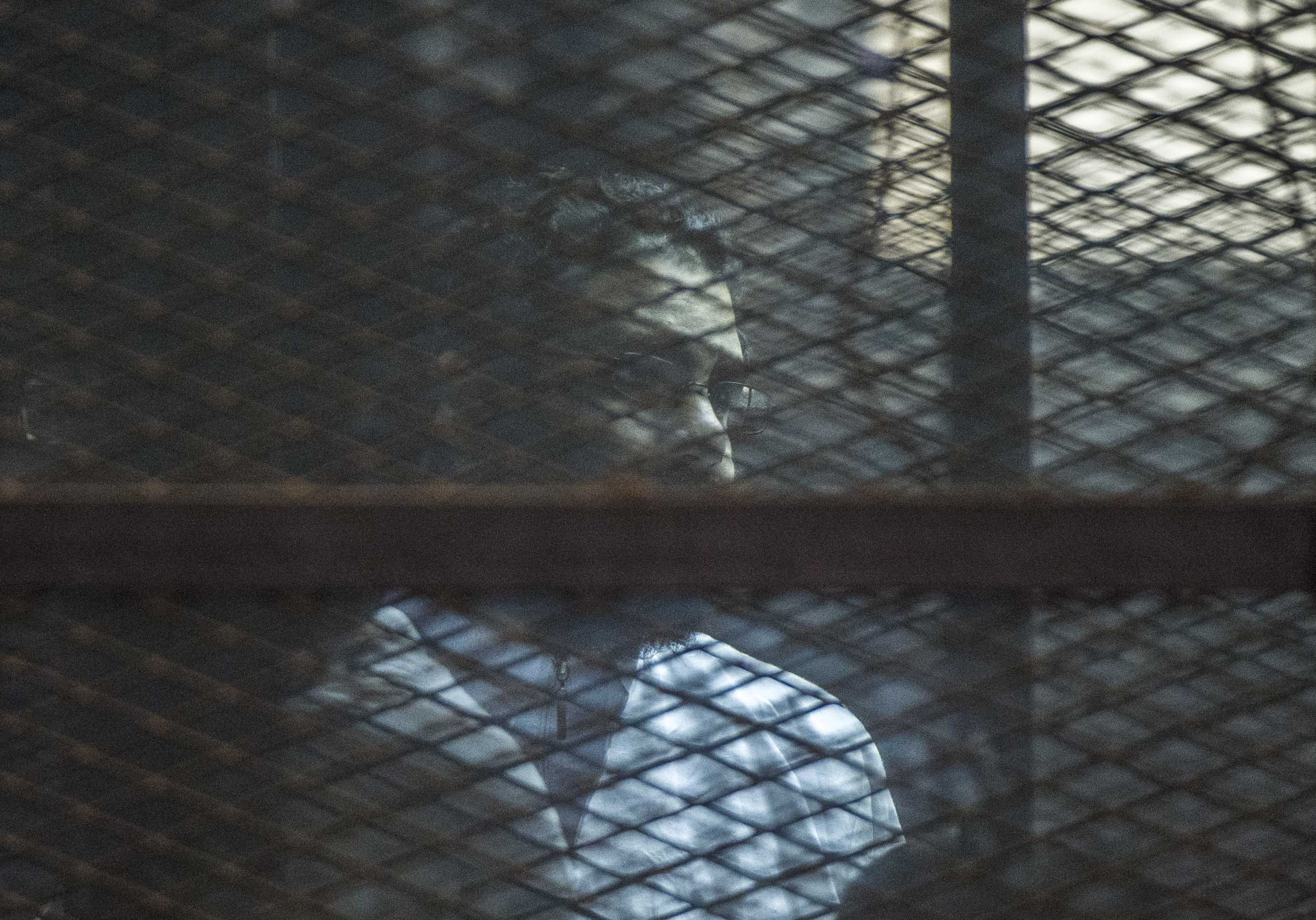Alaa Abdel Fattah stands in a cage during a verdict hearing over an unauthorised street protest in 2013, in a courtroom in Cairo