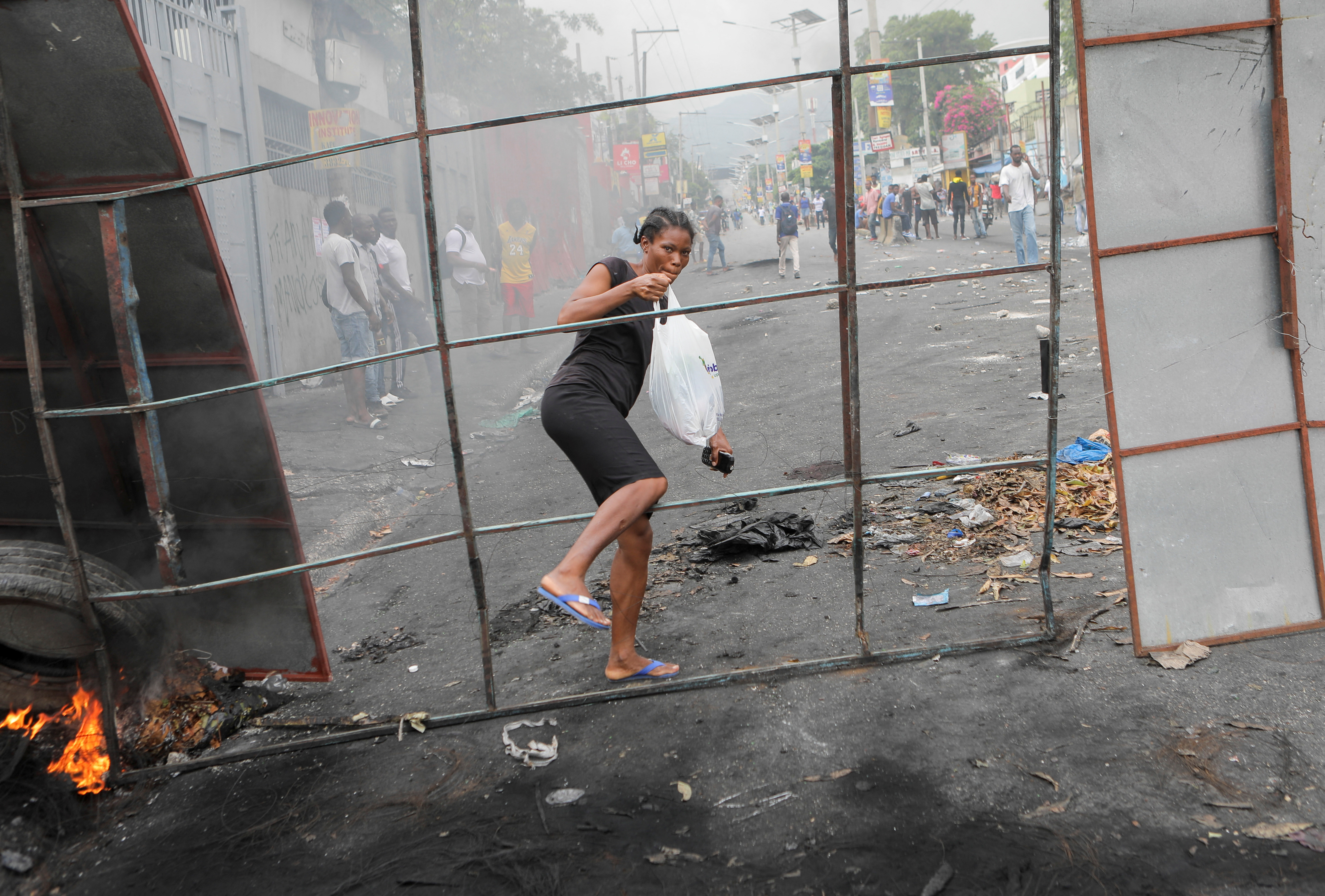 A woman crosses a barricade set up by demonstrators in Haiti's capital of Port-Au-Prince as protests rage in Haiti.
