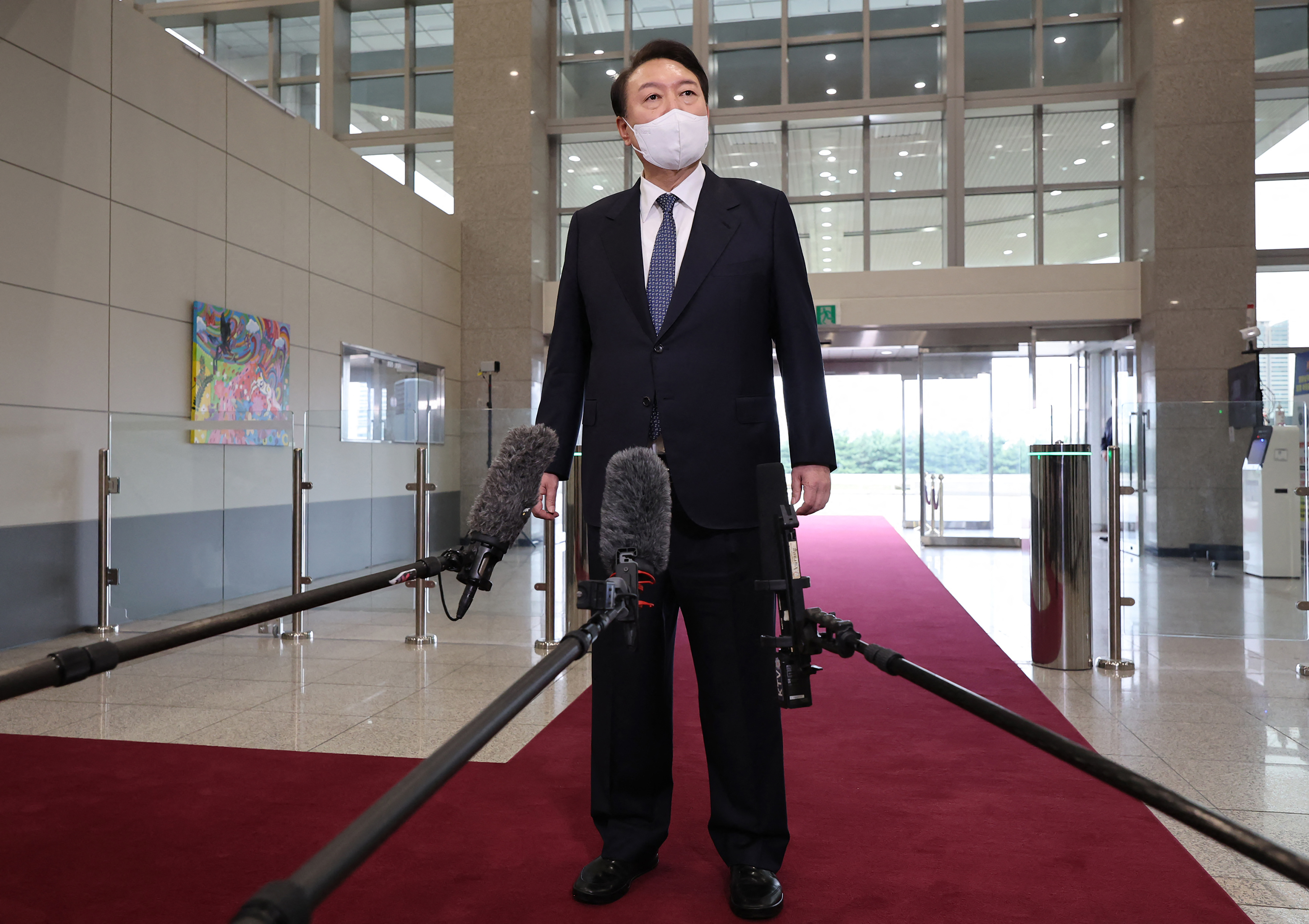 South Korean president Yoon Suk-yeol stands on a red carpet as he speaks to the media after arriving at the presidential office in Seoul