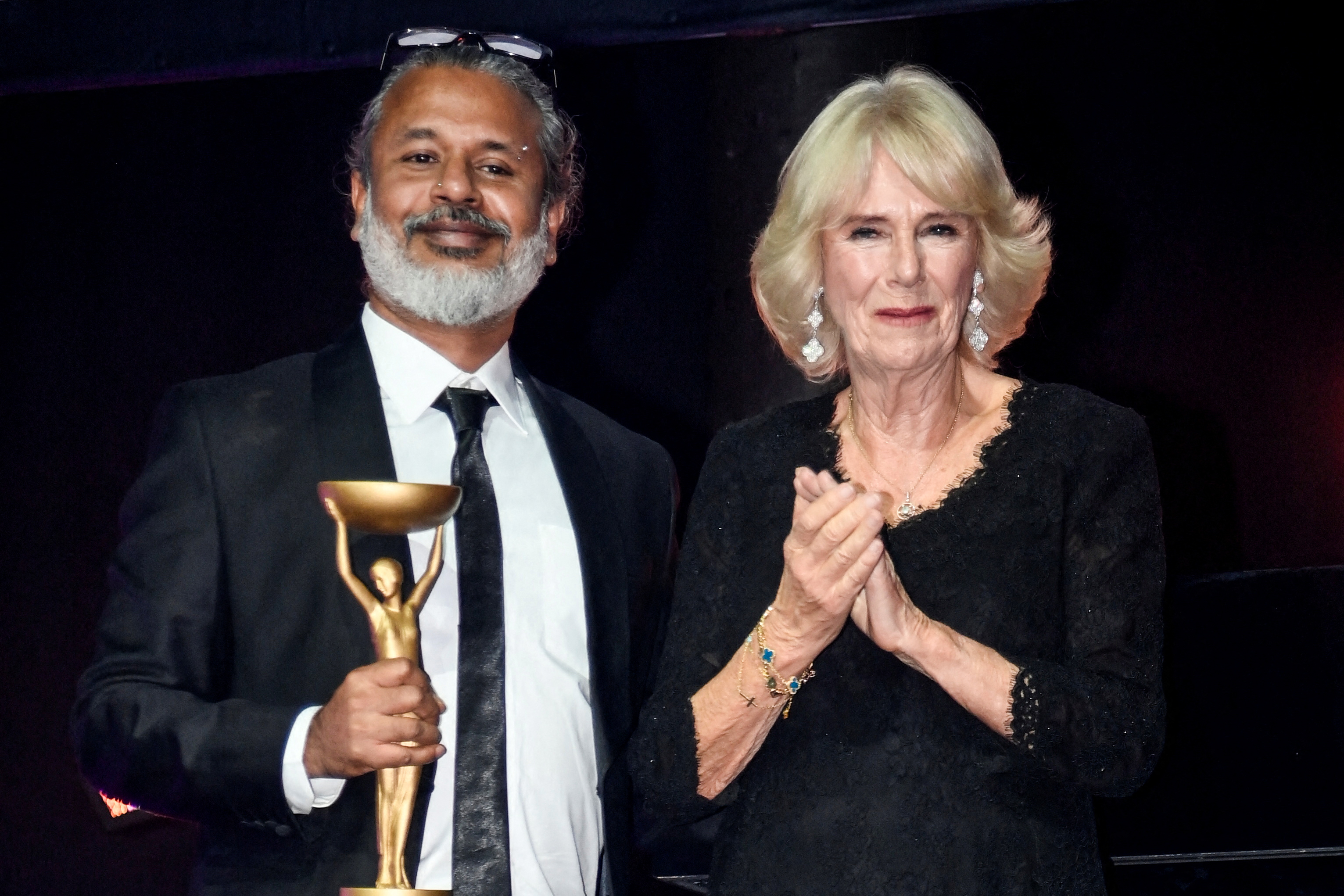 Sri Lankan writer Shehan Karunatilaka poses next to Britain's Camilla, queen consort, holding the golden Booker Prize trophy.