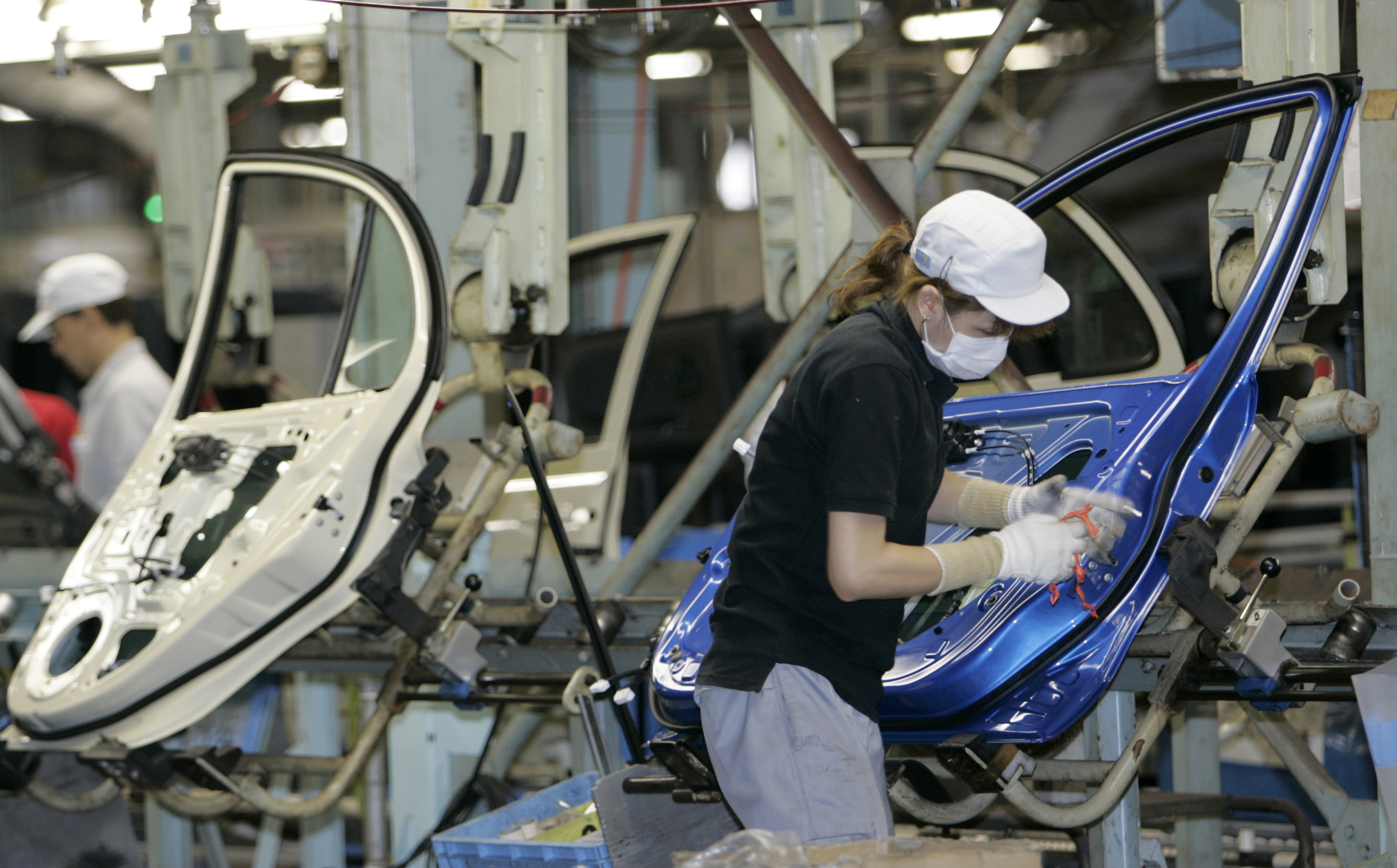 Employees of Nissan Motor Co work on an assembly line at the Oppama factory in Yokosuka, Japan.