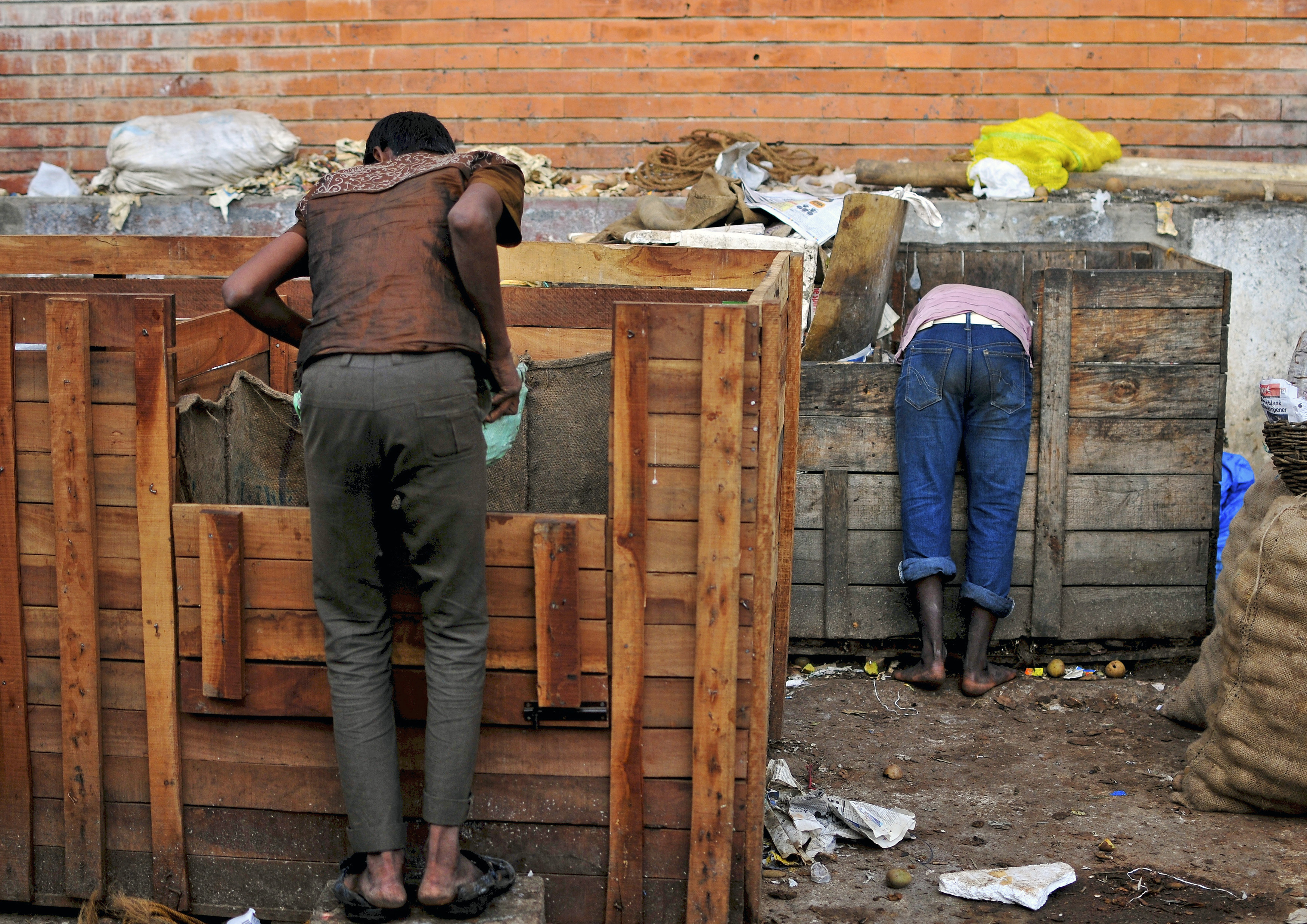 Boys scavenge for leftover fruits from delivery containers outside a fruit market in the southern Indian city of Bangalore October 17, 2014.