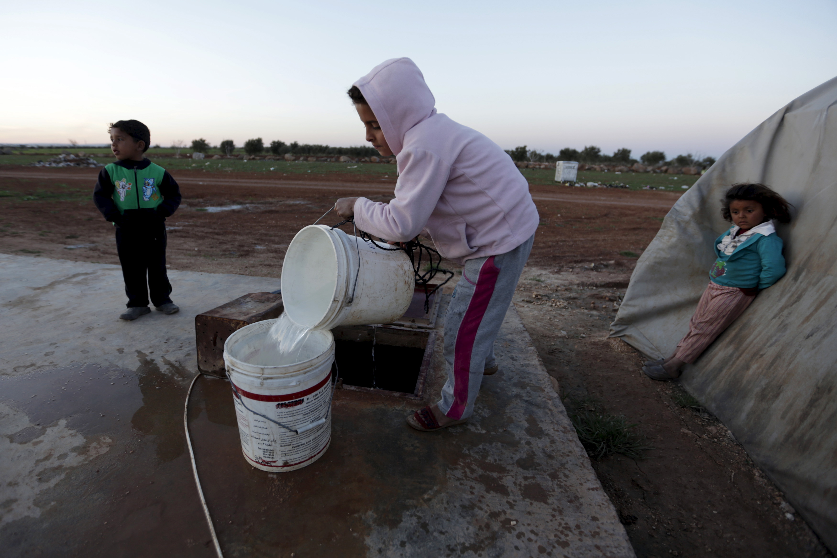 a child pours water into a bucket