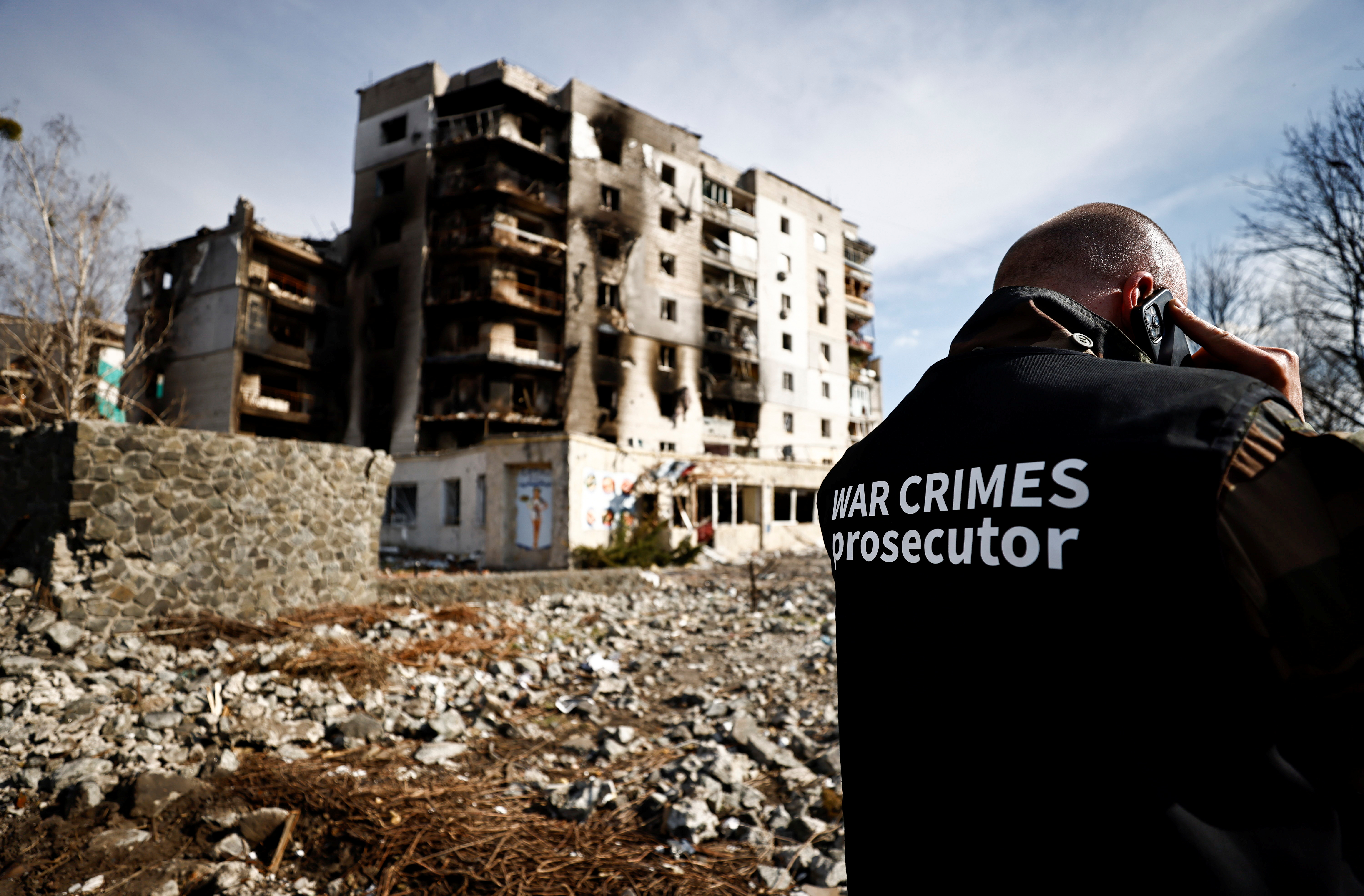 A war crime prosecutor speaks on the phone next to buildings that were destroyed by Russian shelling, amid Russia's Invasion of Ukraine, in Borodyanka, Kyiv on April 7