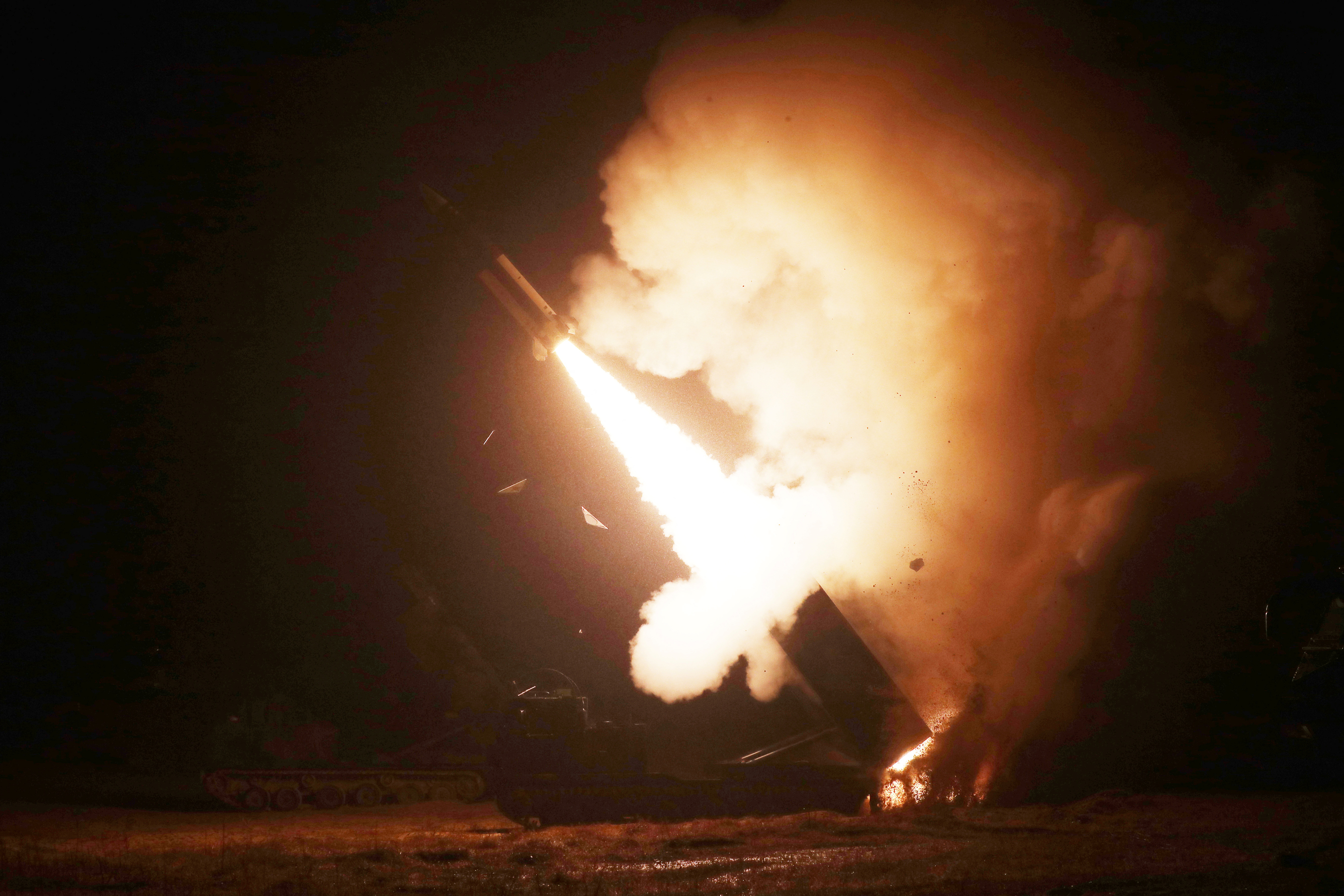A missile being launched at night amid clouds of smoke and flames.