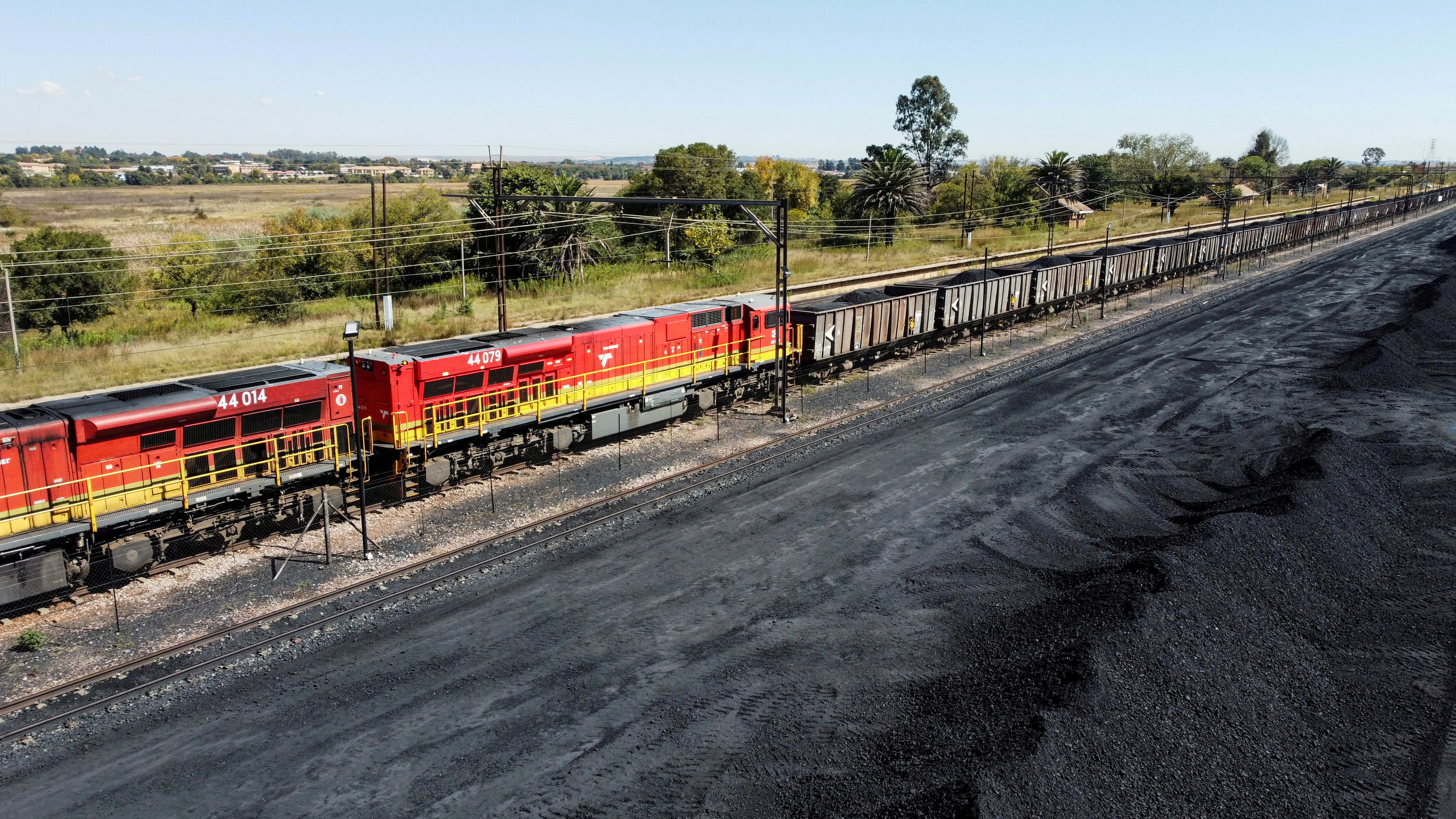 FILE PHOTO: A Transnet Freight Rail train is seen next to tons of coal mined from the nearby Khanye Colliery mine, at the Bronkhorstspruit station, in Bronkhorstspruit, around 90 kilometres north-east of Johannesburg, South Africa, April 26, 2022. REUTERS/Siphiwe Sibeko/File Photo