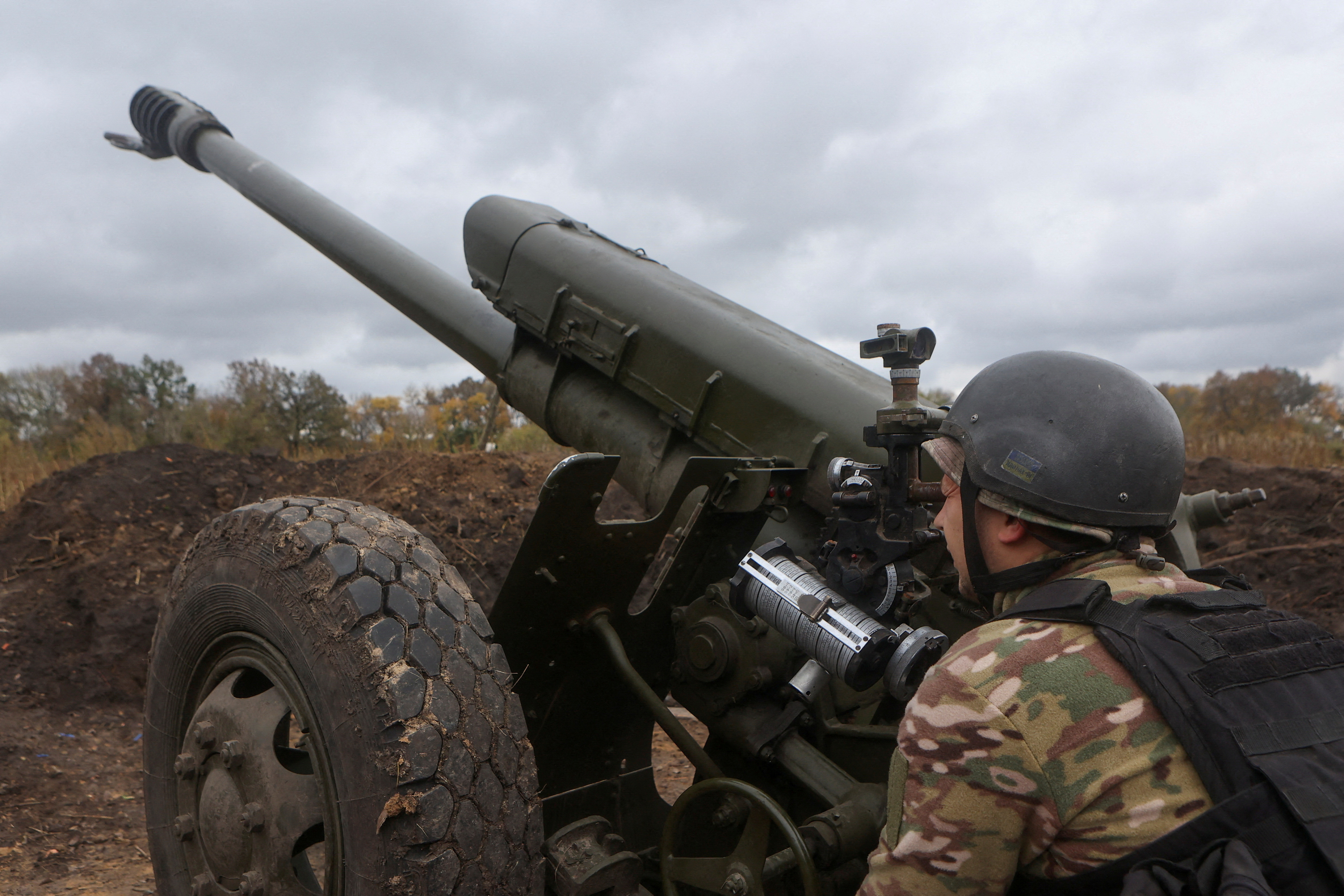 Soldiers looking through eye-piece of howitzer