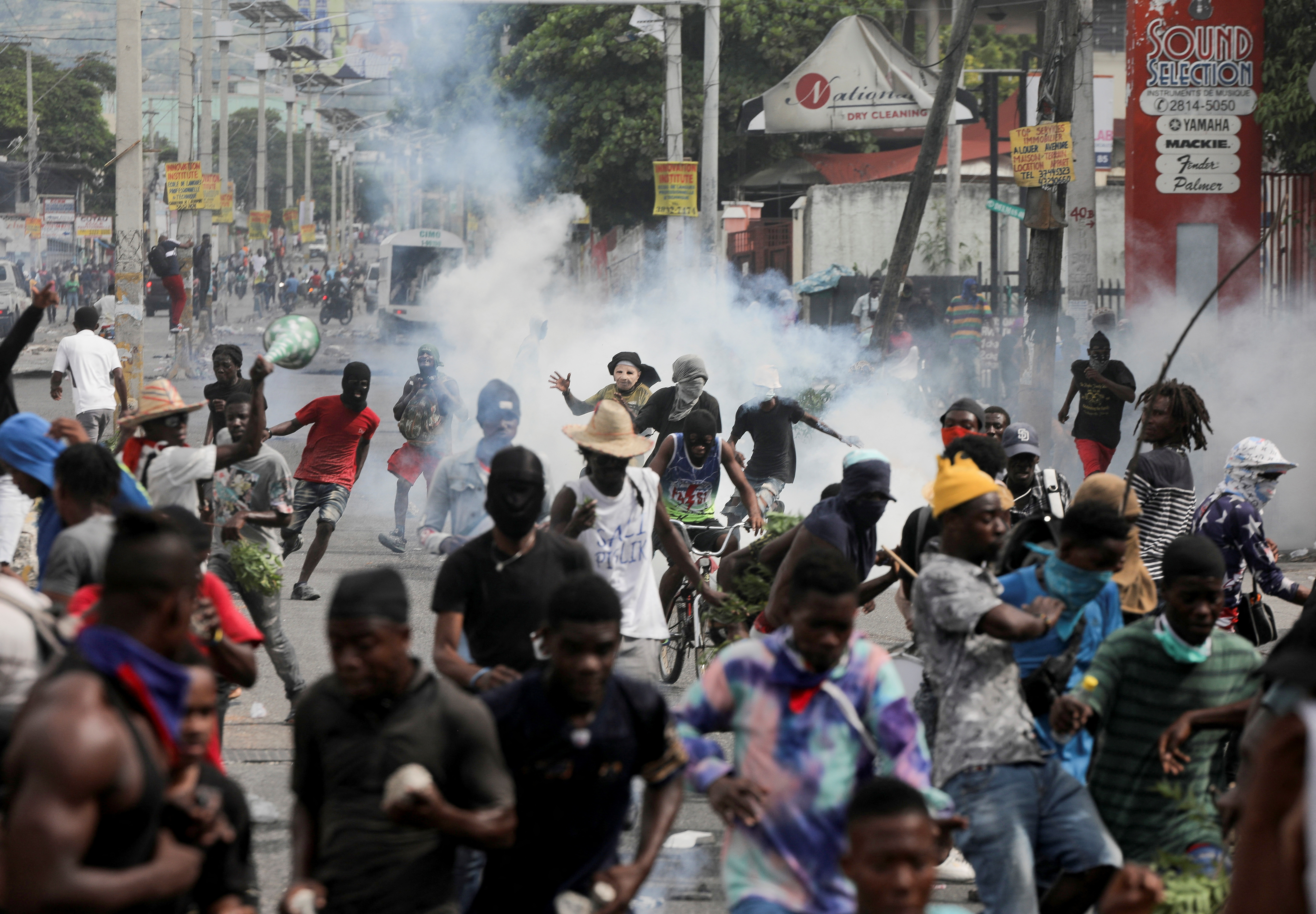 People run while police fire tear gas during a protest demanding the resignation of Haiti's Prime Minister Ariel Henry after weeks of shortages, in Port-au-Prince, Haiti October 10, 2022. REUTERS/Ralph Tedy Erol