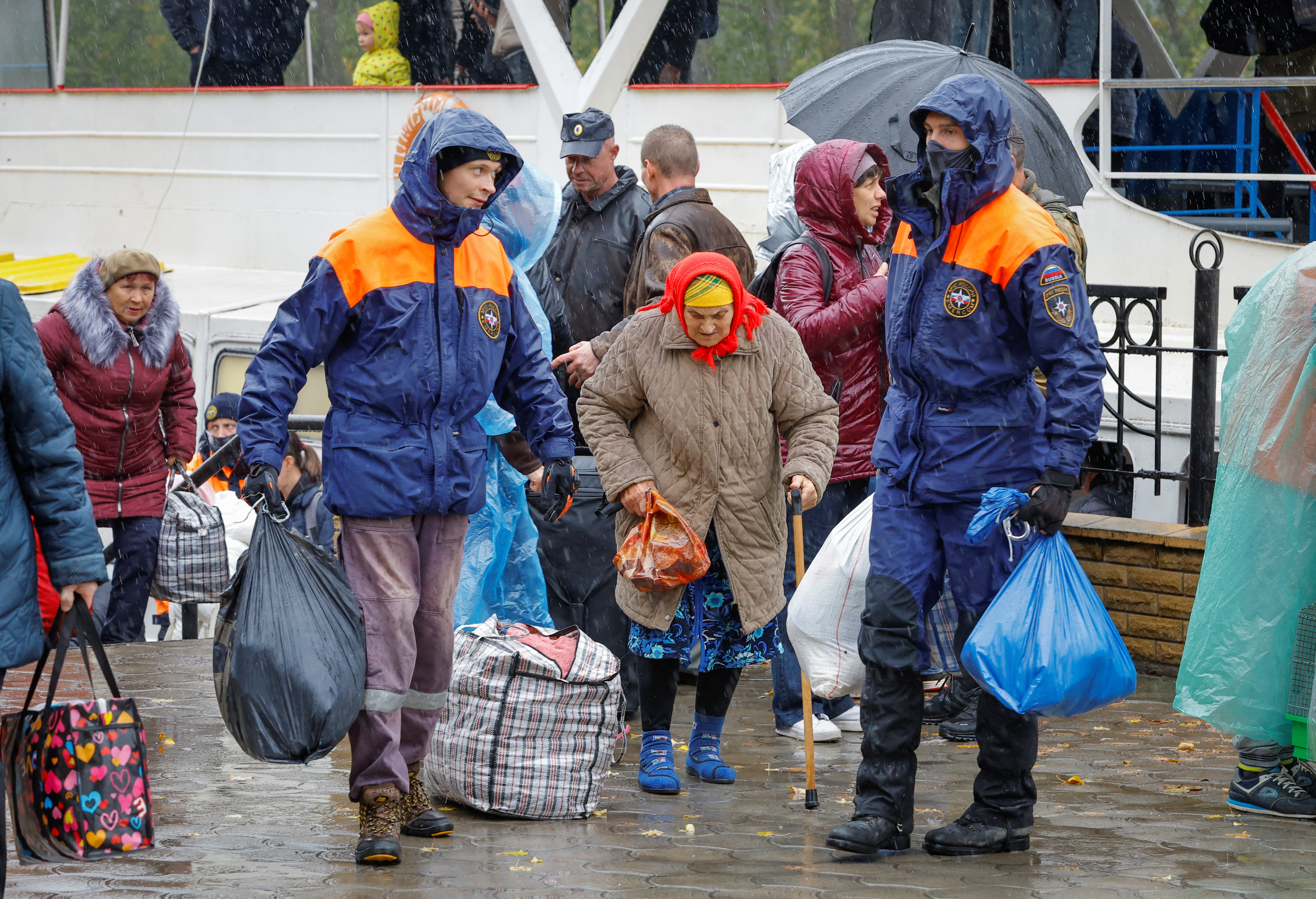 Civilians evacuated from the Russian-controlled city of Kherson walk from a ferry to board a bus heading to Crimea, in the town of Oleshky, Kherson region, Russian-controlled Ukraine October 23, 2022. REUTERS/Alexander Ermochenko