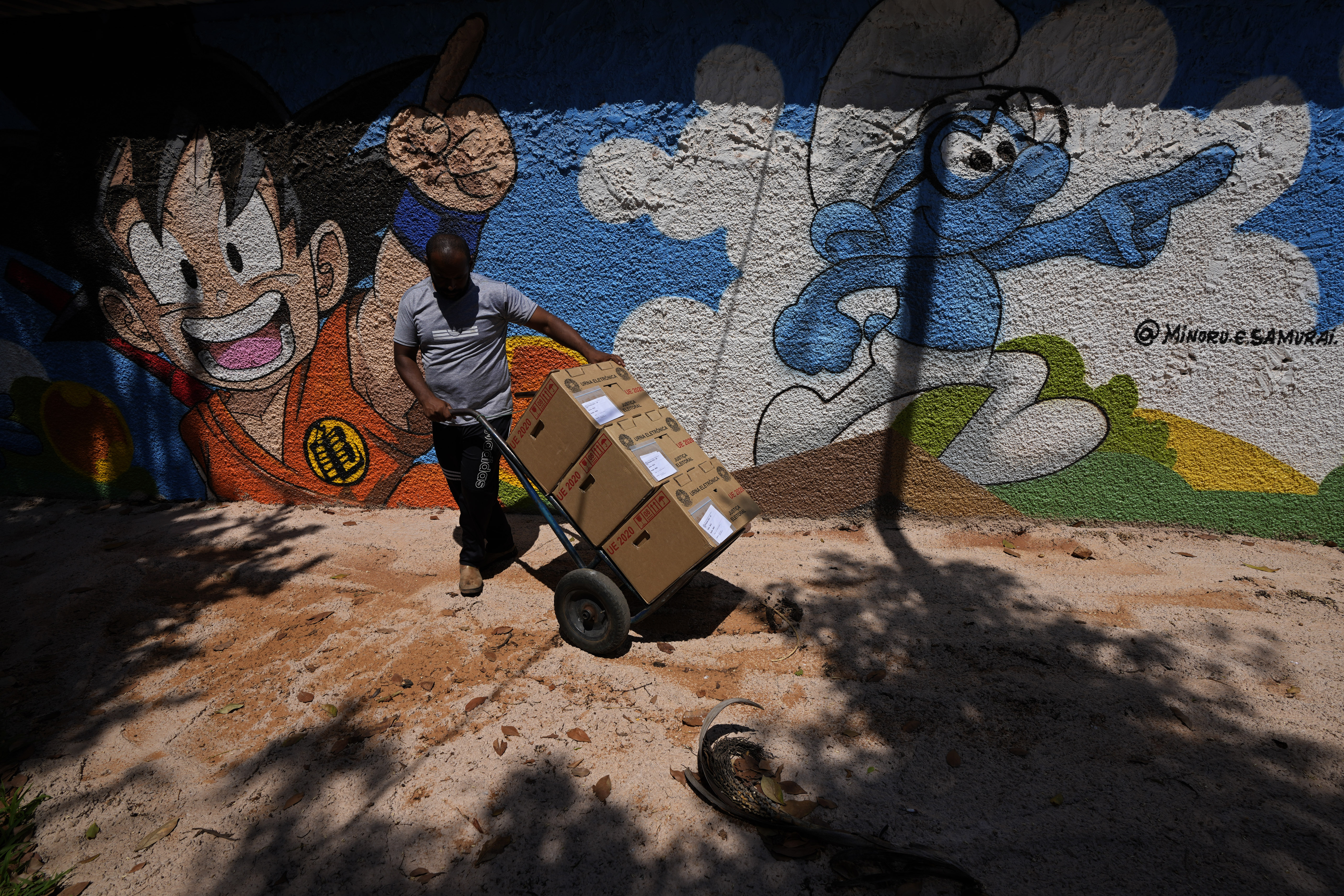 An electoral worker pushes a dolly of electronic voting machines, delivered to a polling station at a school in preparation for the upcoming general election, in Brasilia, Brazil, Friday, Sept. 30, 2022. Brazilians head to polls on Oct. 2 to elect a president, vice president, governors and senators. (AP Photo/Eraldo Peres)
