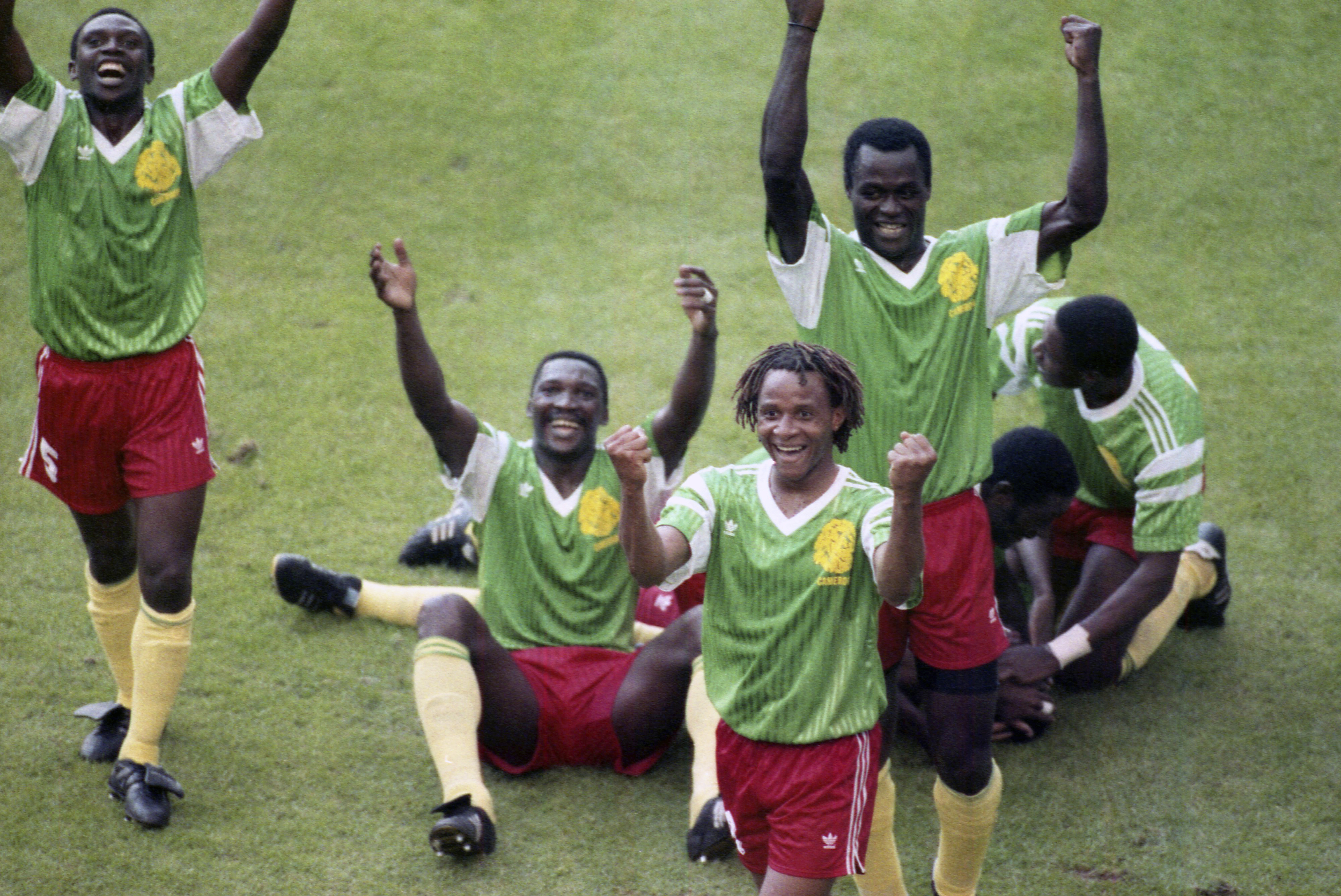 Members of the Cameroon national soccer team raise their arms and jubilate