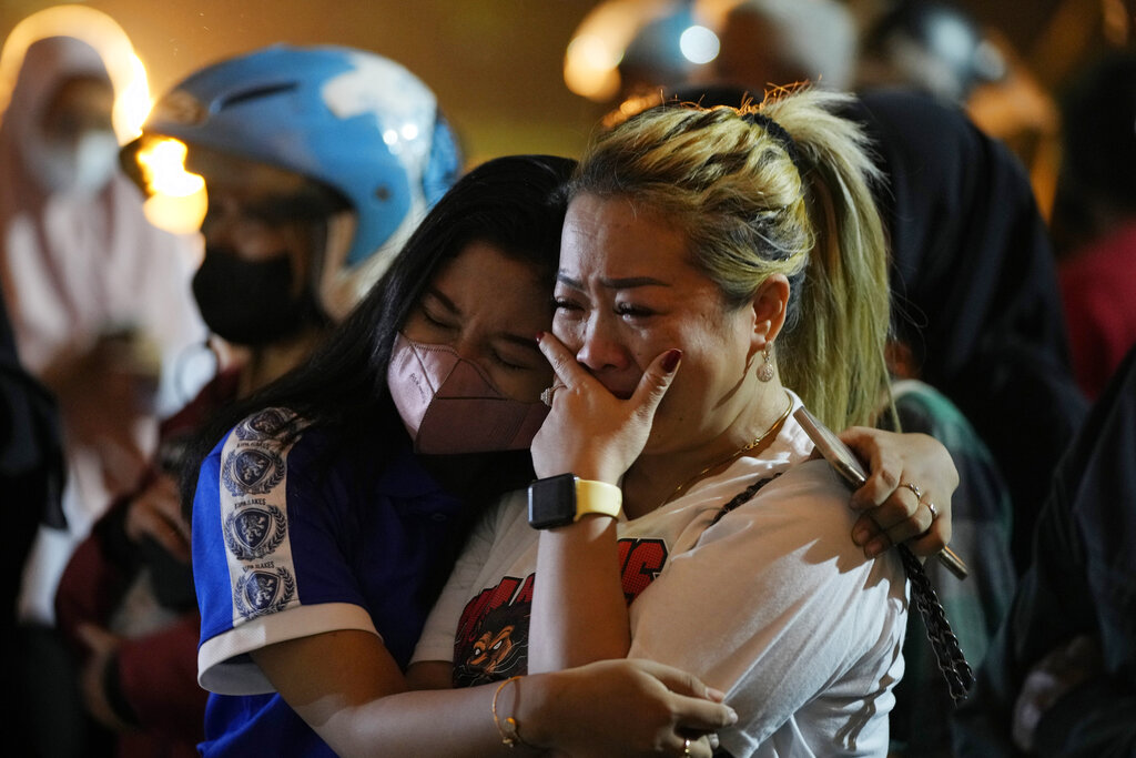 A woman weeps as she offers prayers in front of gate 13 at the Kanjuruhan Stadium in Malang, Indonesia on October 4, 2022 [Achmad Ibrahim/AP]