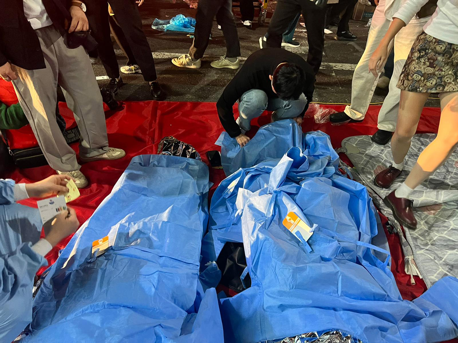 A man covers the dead in Seoul's Itaewon entertainment district after a stampede during Halloween festivities on Saturday.