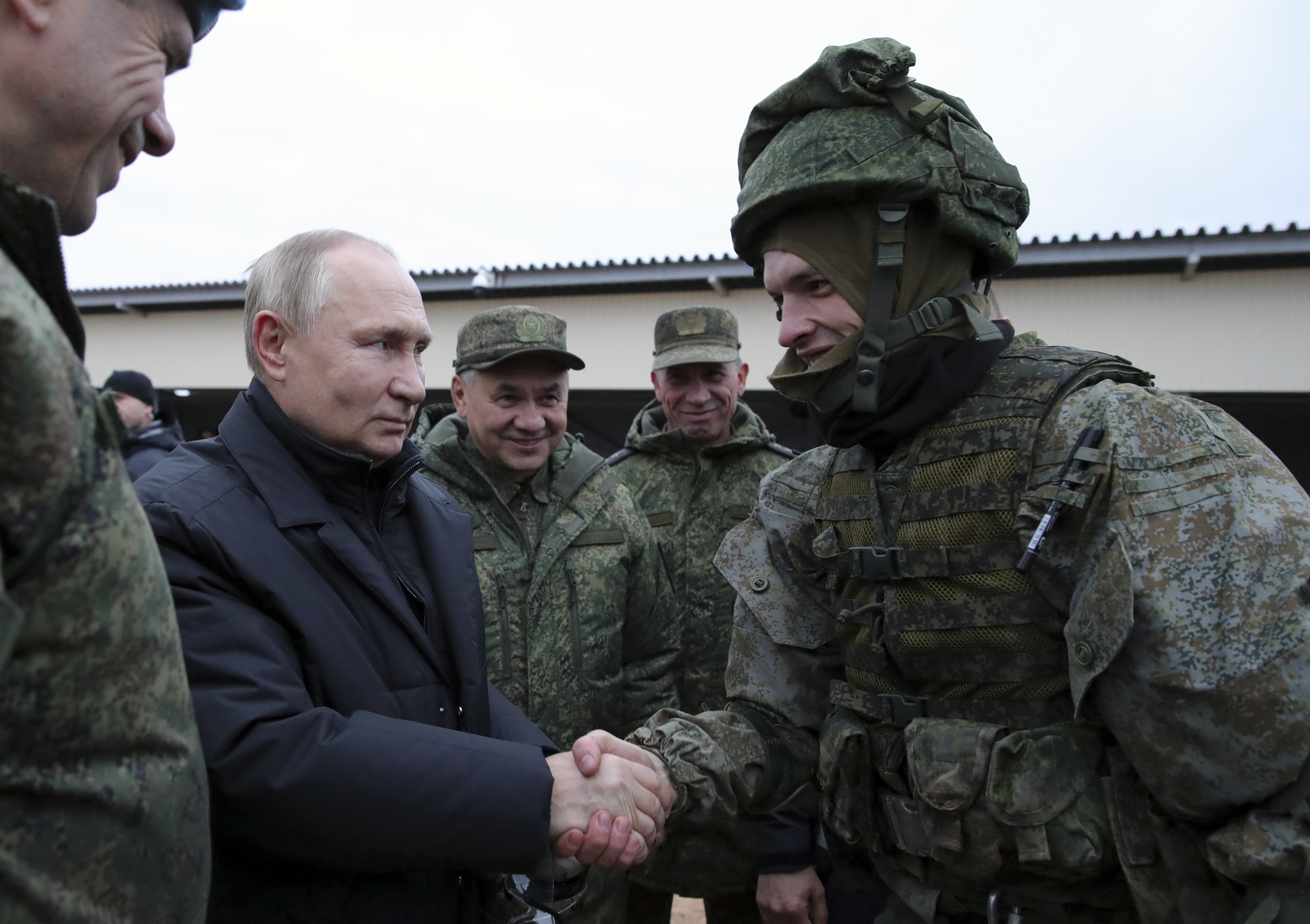 Russian President Vladimir Putin shakes the hand of a service member as Russian Defence Minister Sergei Shoigu looks on with other officers at a training range in the Ryazan region, Russia.