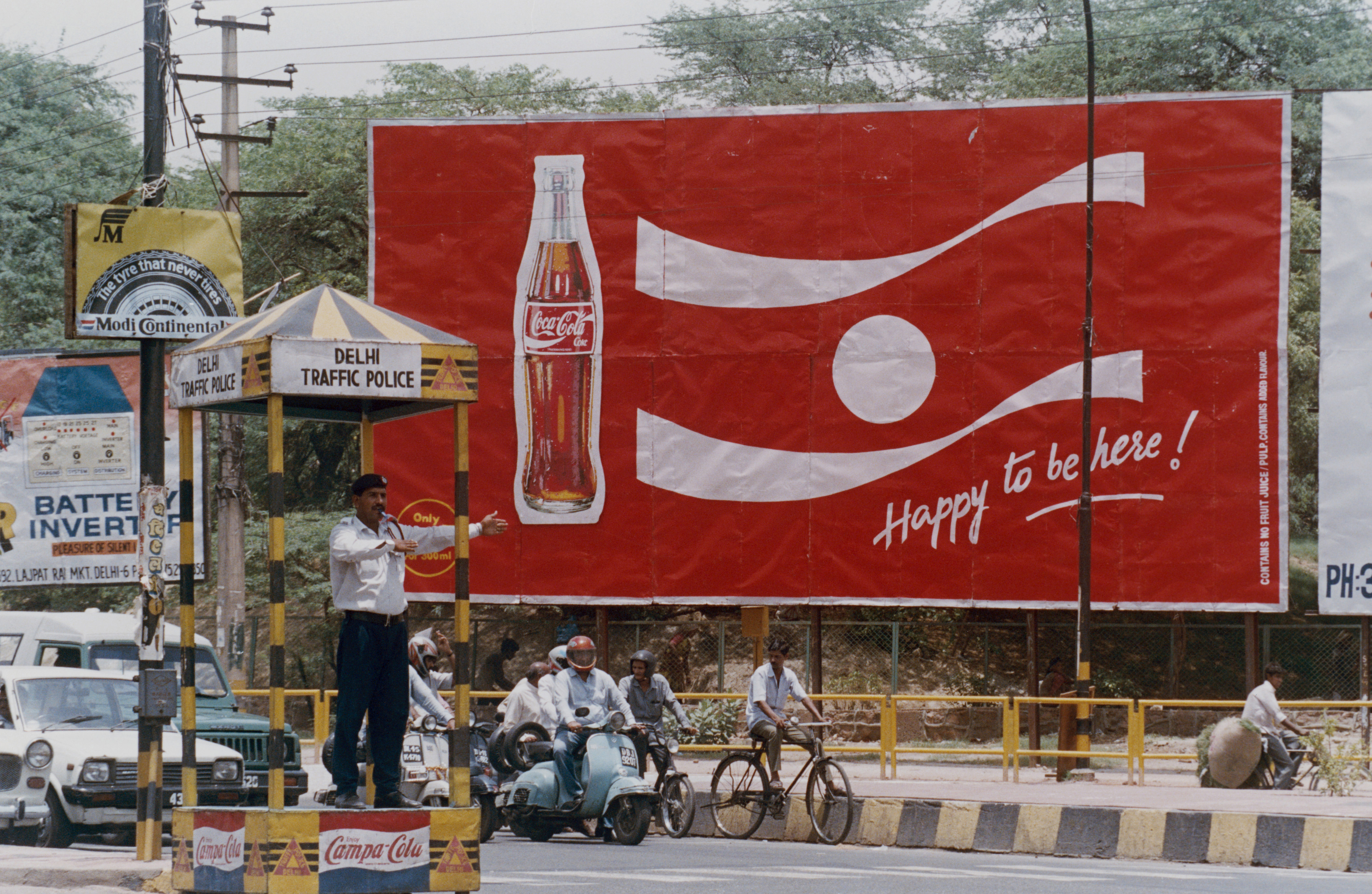 A traffic policeman directs traffic at a busy junction in front of a billboard for a new Coca-Cola advertising campaign in New Delhi.