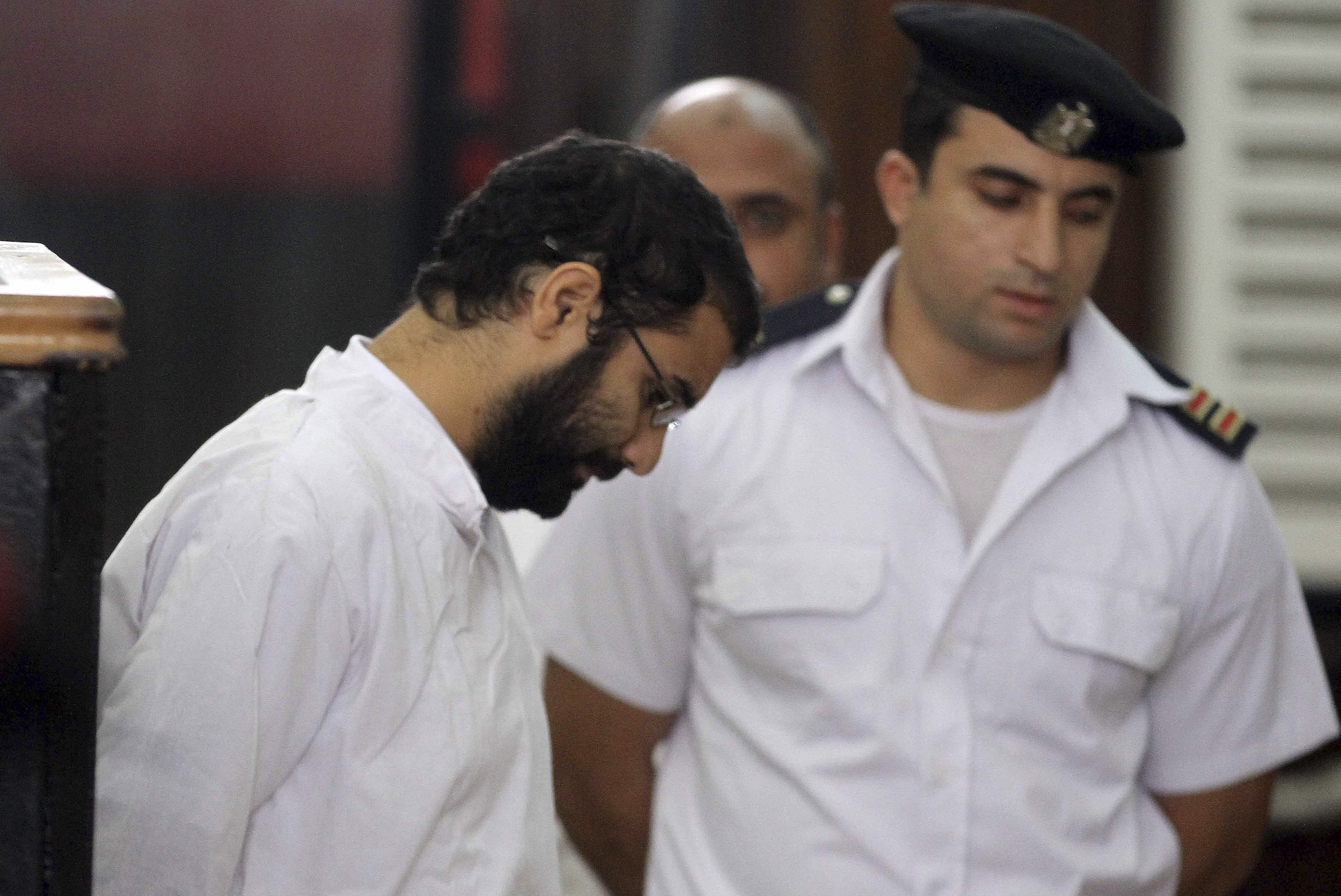 Activist Alaa Abdel Fattah stands in front of a police officer at a court during his trial in Cairo, November 11, 2014.