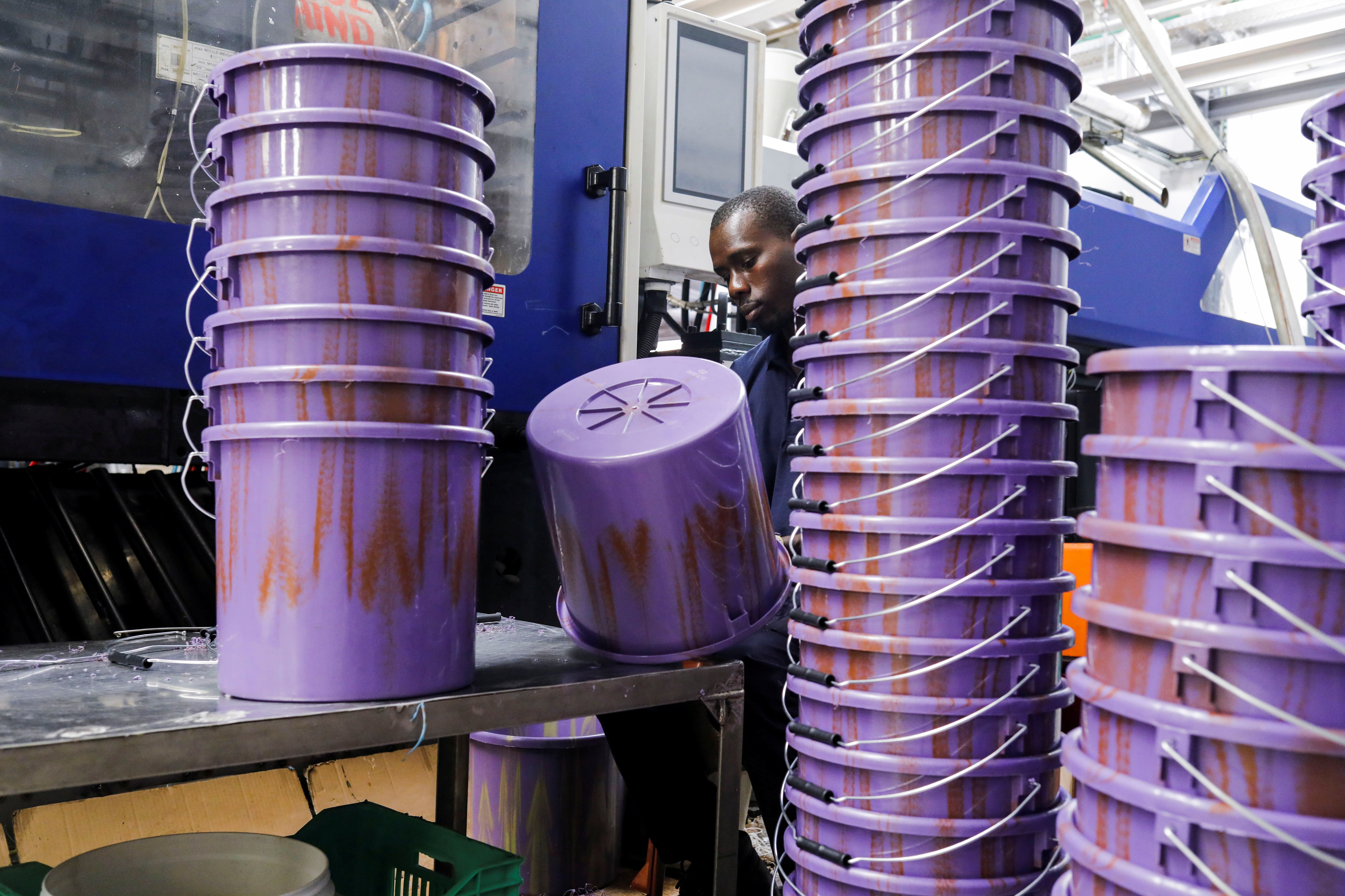 A worker checks newly made buckets from recycled plastic.