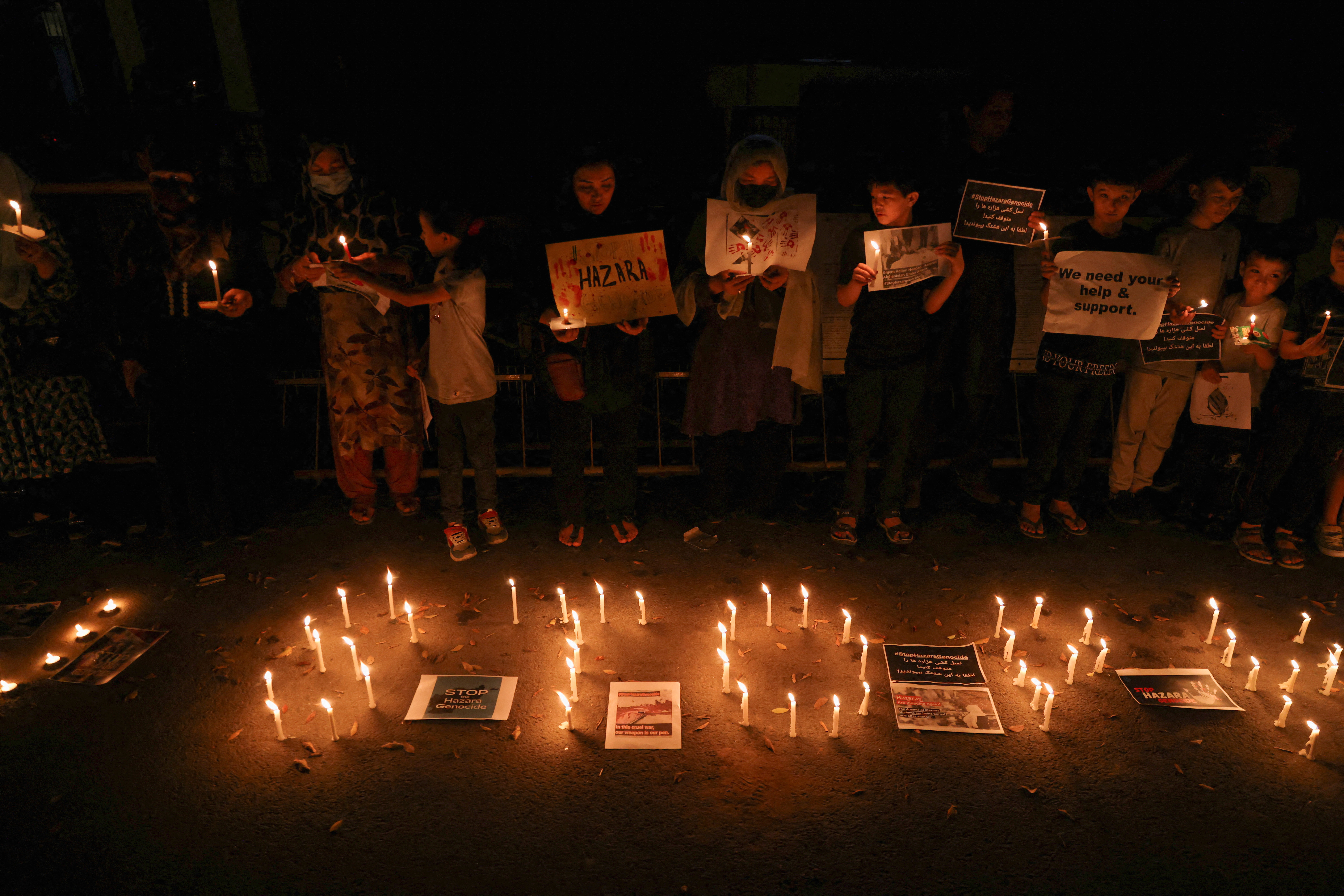 Afghan nationals, members of the Hazara minority, hold placards and candles as they protest against the suicide attack at a tutoring center in west Kabul, outside the United Nations High Commissioner for Refugees (UNHCR) office, in New Delhi, India, September 30, 2022. REUTERS/Anushree Fadnavis REFILE - QUALITY REPEAT