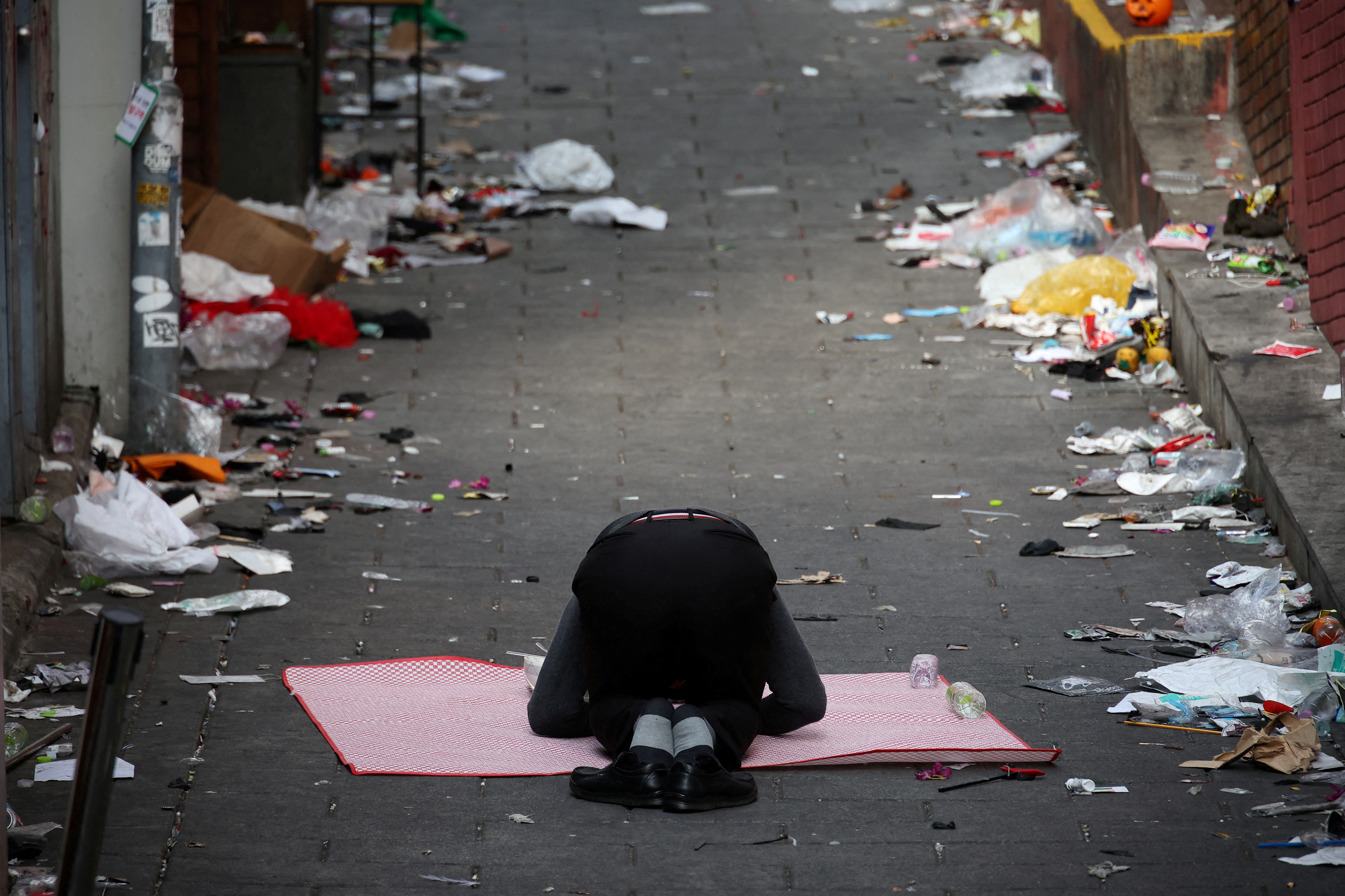 Clerk of nearby store kneeling at site of tragedy.