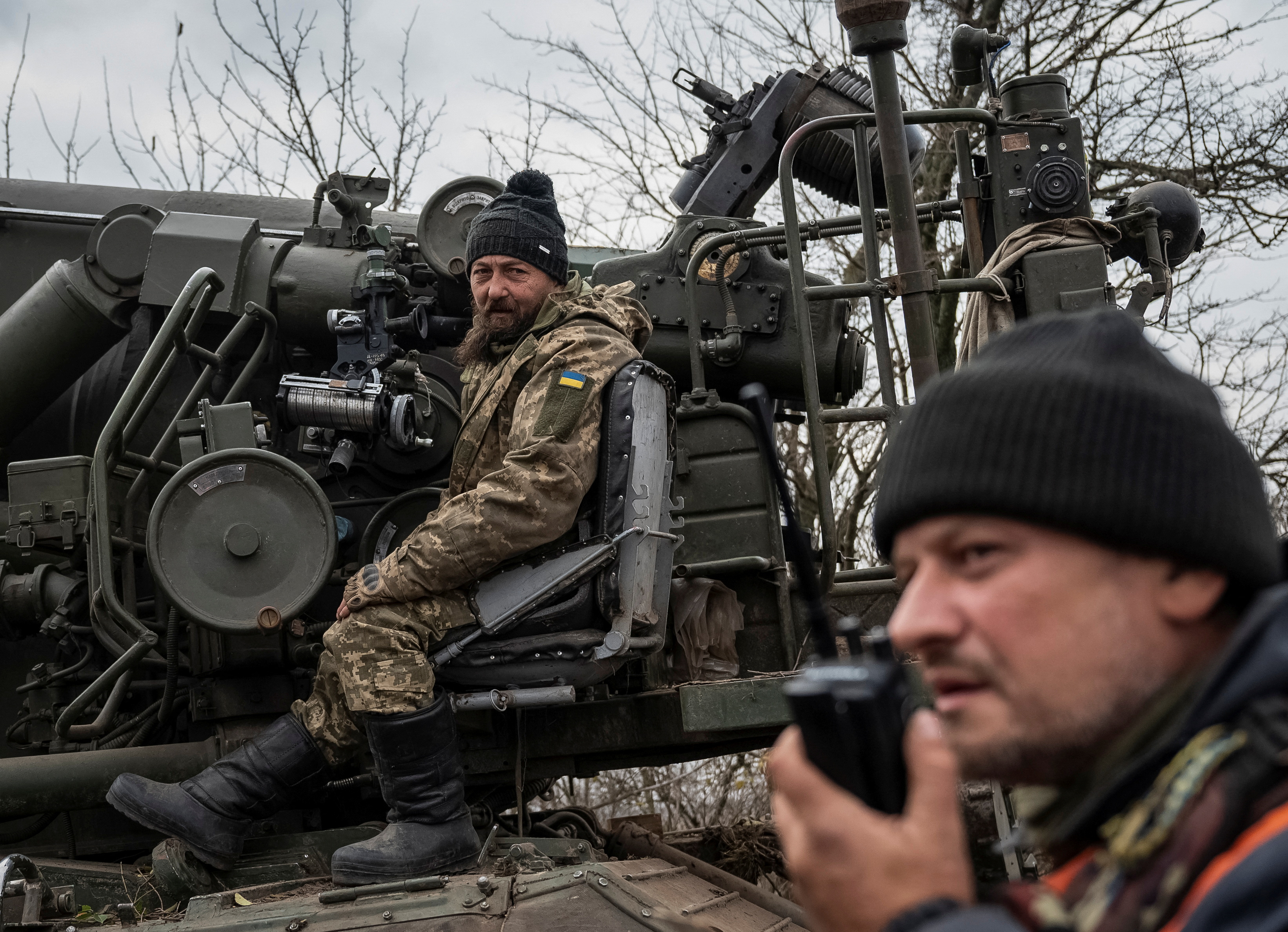 Ukrainian soldiers, the one closest to the camera speaking on a walkie talkie and the one behind preparing to fire a 2S7 Pion self-propelled gun at Russian positions in Kherson region