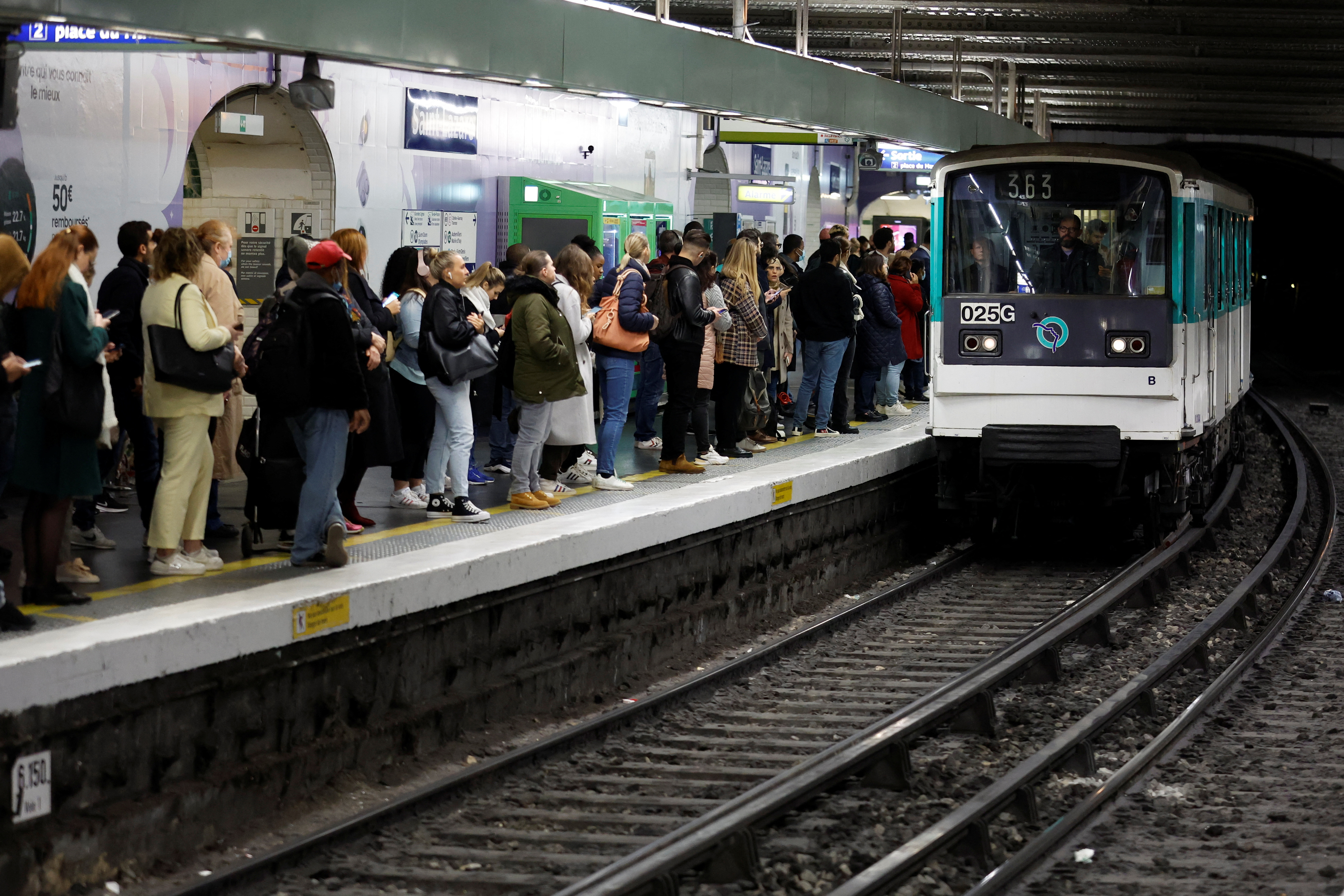 People stand at Gare Saint-Lazare metro station during a nationwide strike for higher wages and pensions in Paris