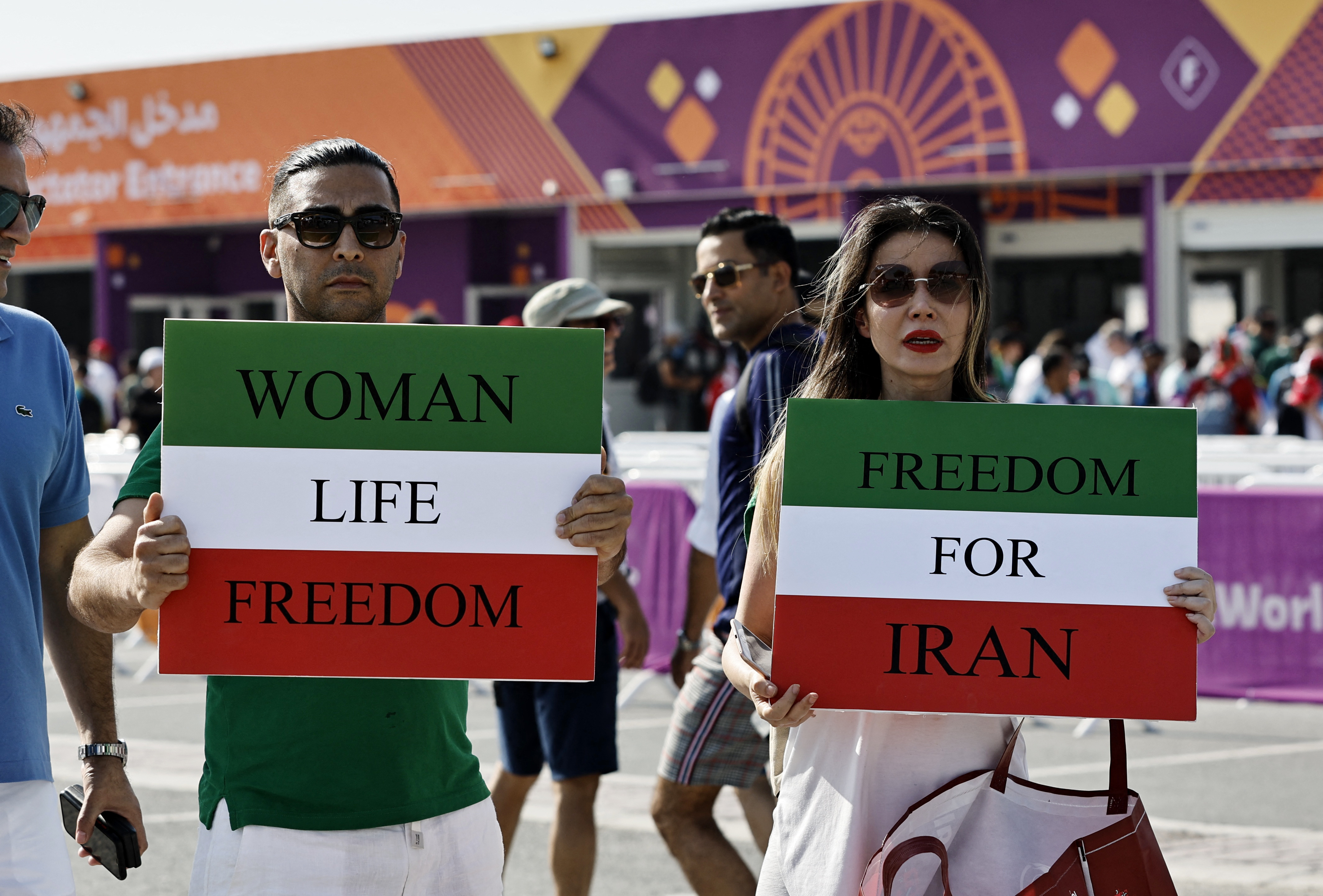 Iranians hold up posters in support of anti-government protests outside a stadium in Qatar