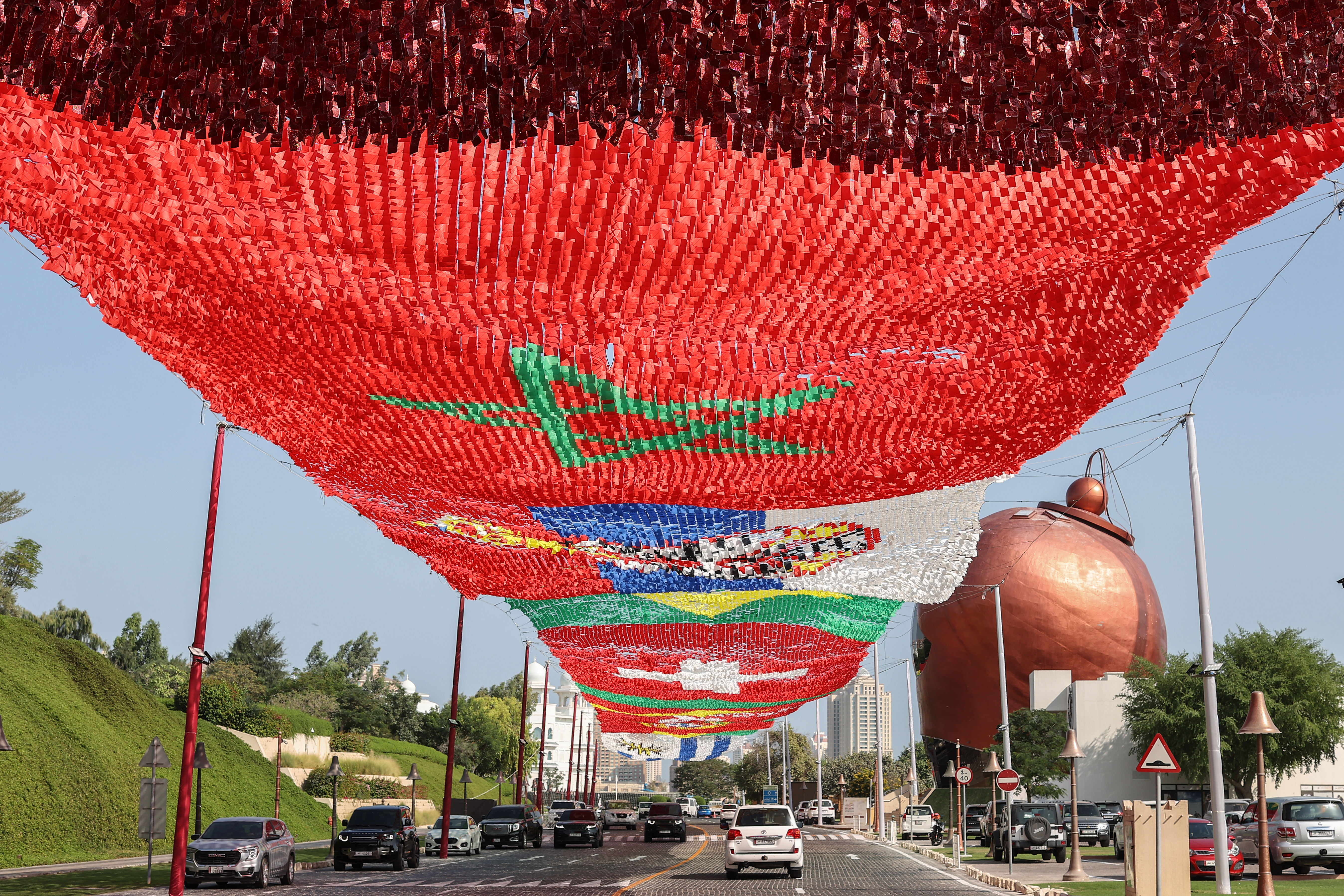 Vehicles driving under a canopy of giant flags from competing countries ahead of the World Cup, In Katara cultural village, Doha, Qatar