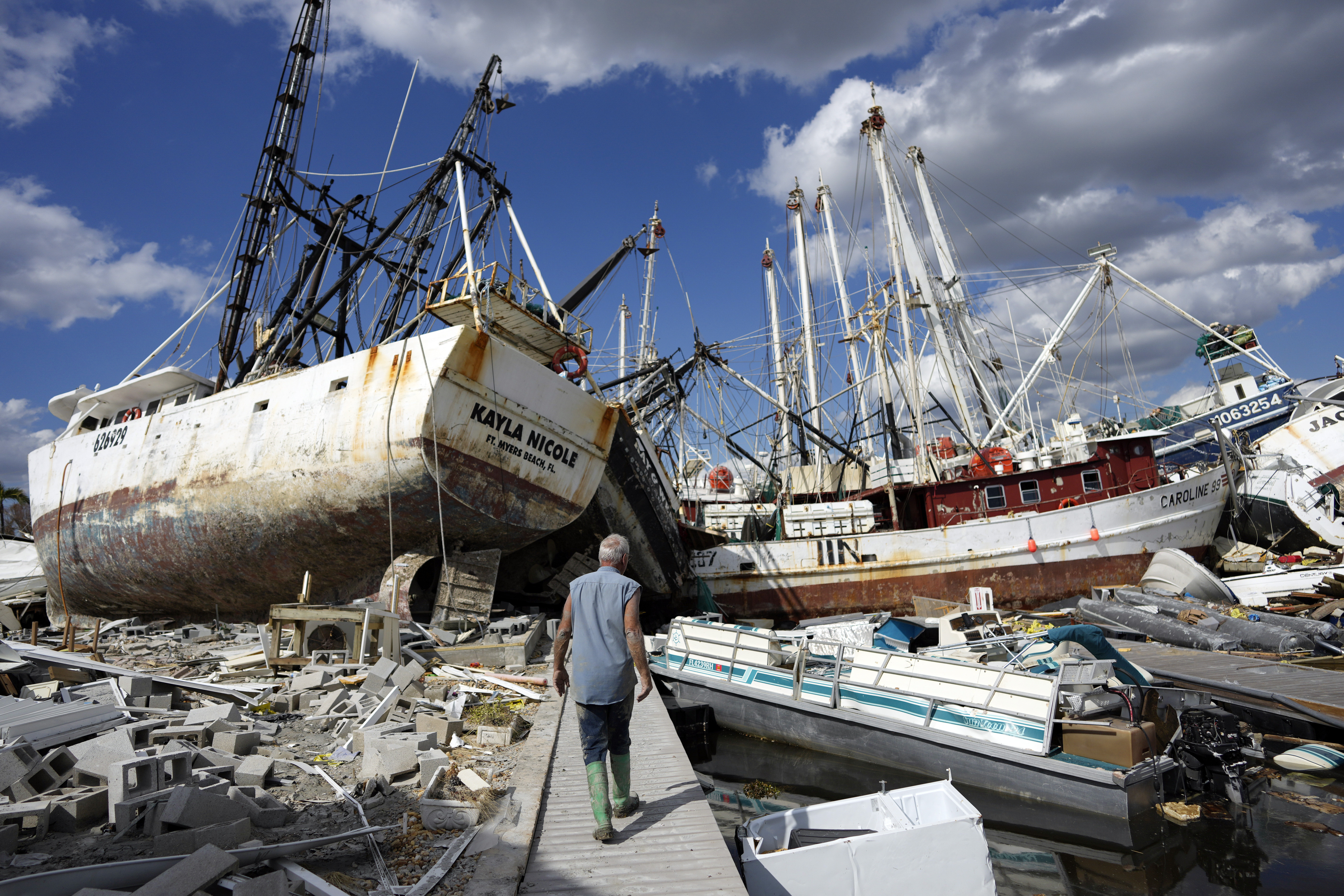 a man walks along the waterfront, now littered with debris