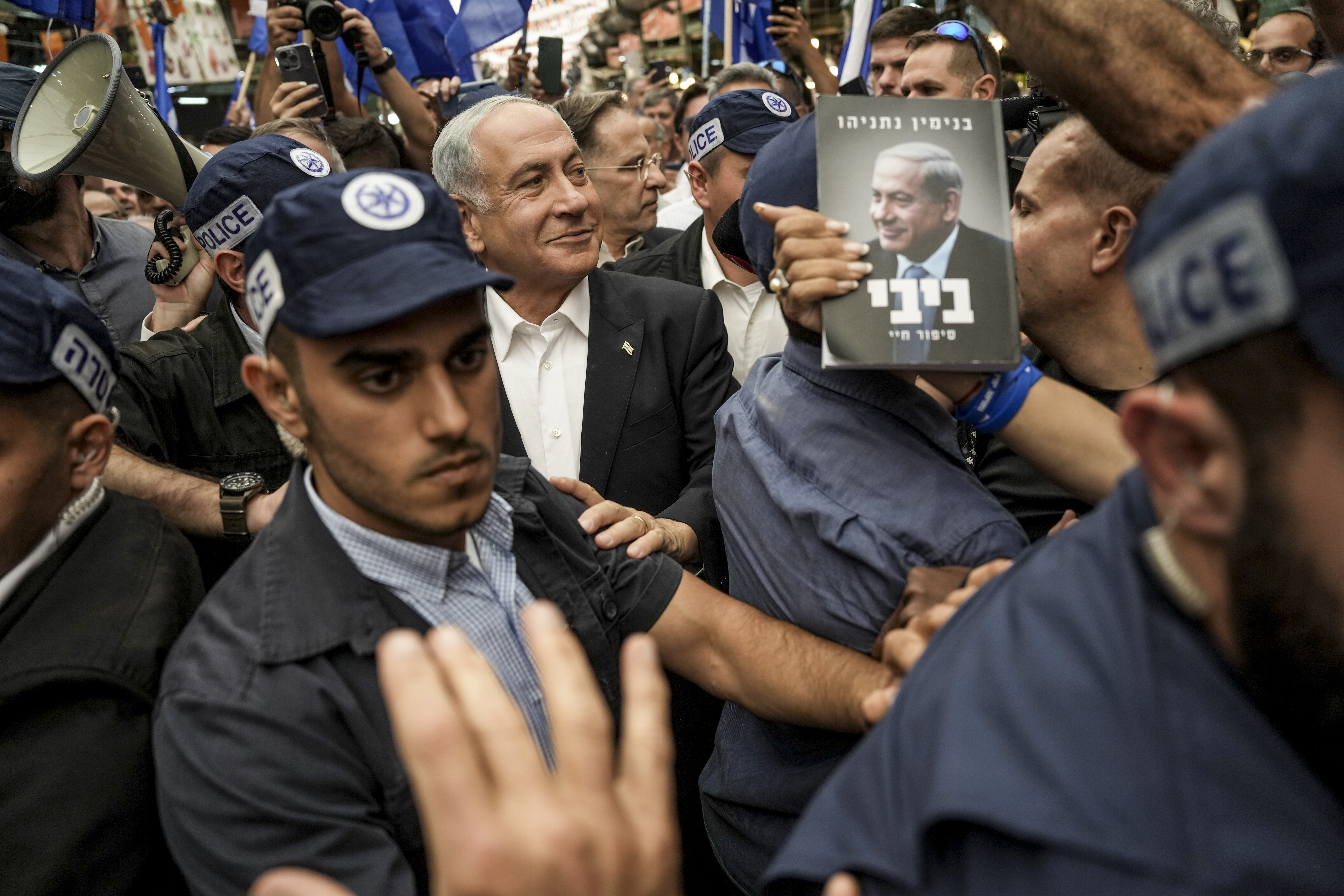 Likud party head and former Israeli Prime Minister Benjamin Netanyahu, center, surrounded by security and his supporters visits at Hatikva Market in Tel Aviv, Israel, Friday, Oct. 28, 2022, during his campaign ahead of the country's election. Israel is heading into its fifth election in under four years on Nov. 1, 2022. (AP Photo/Ariel Schalit)