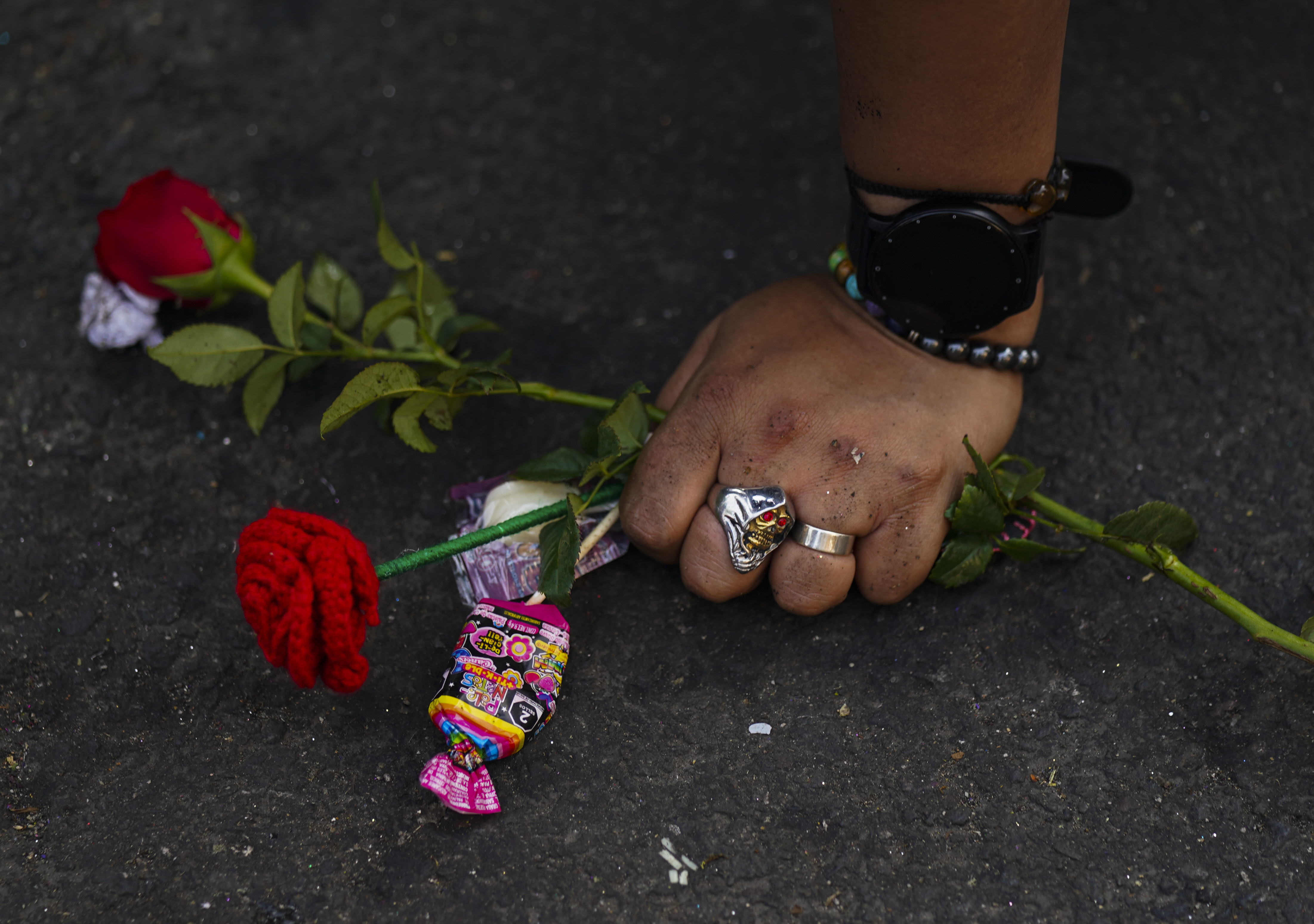 A woman's hand on the ground holding flowers.