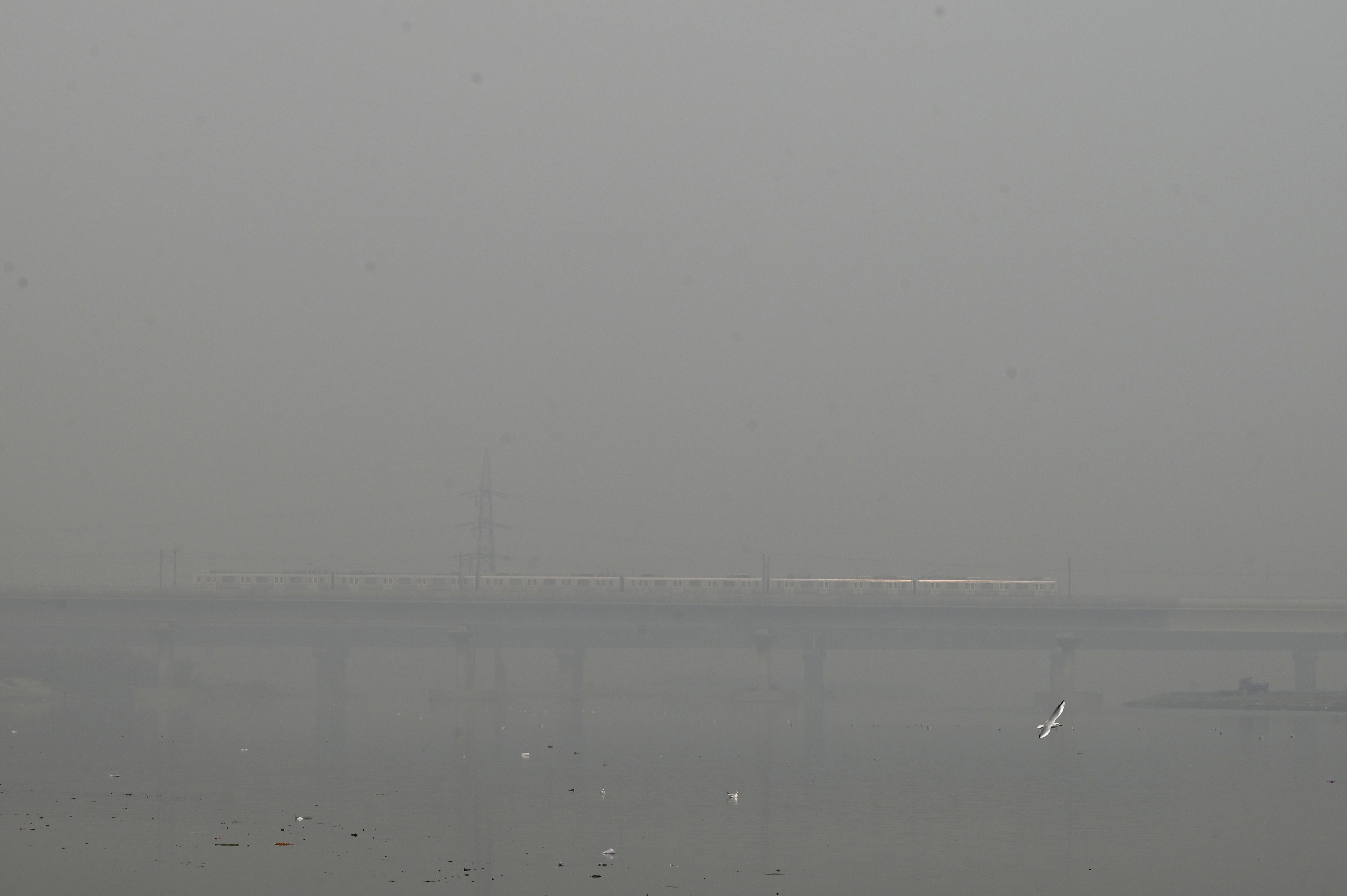 A metro train runs on a bridge enveloped by smog and haze in New Delhi.