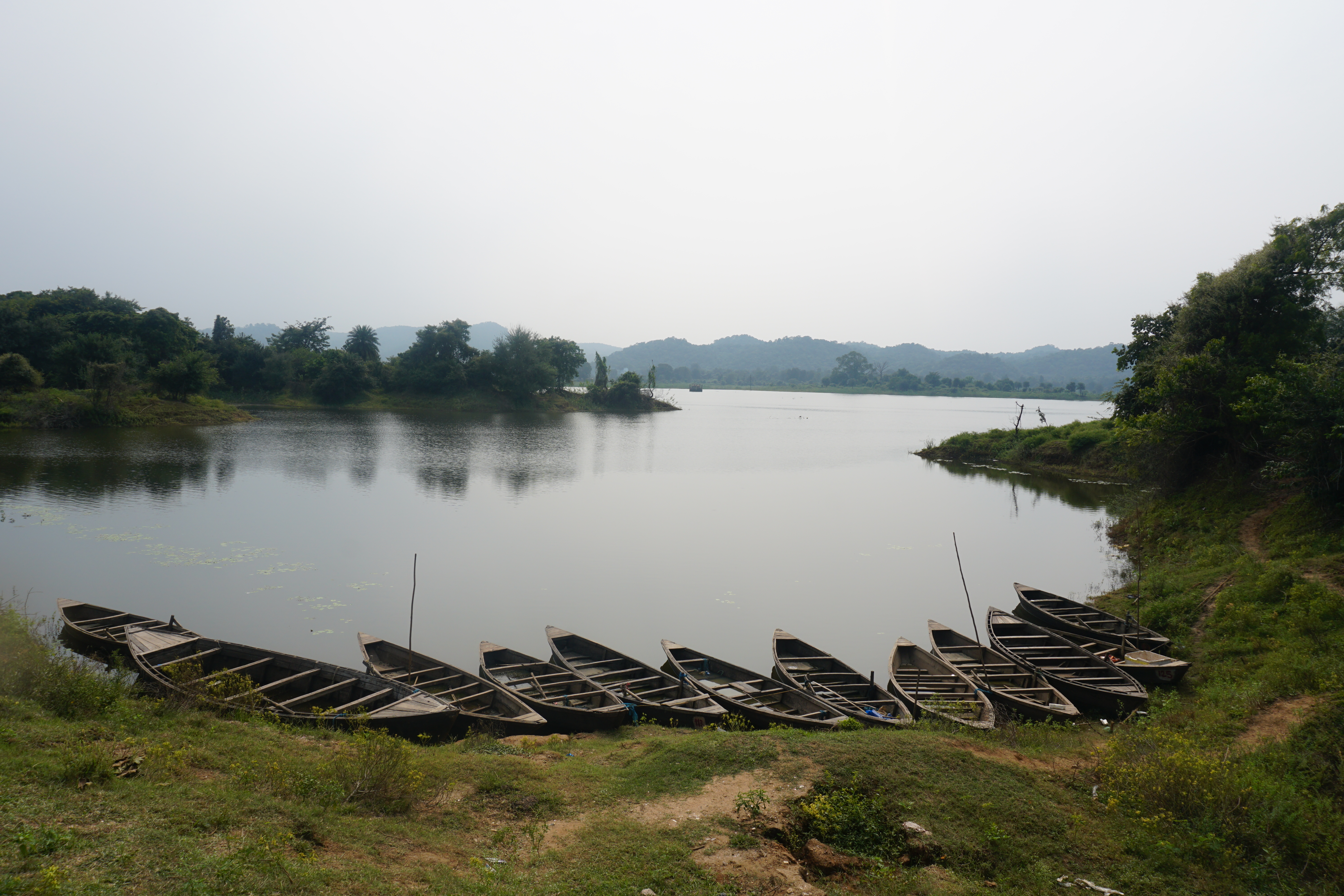 A photo of boats on the shore with a large body of water behind the boats.