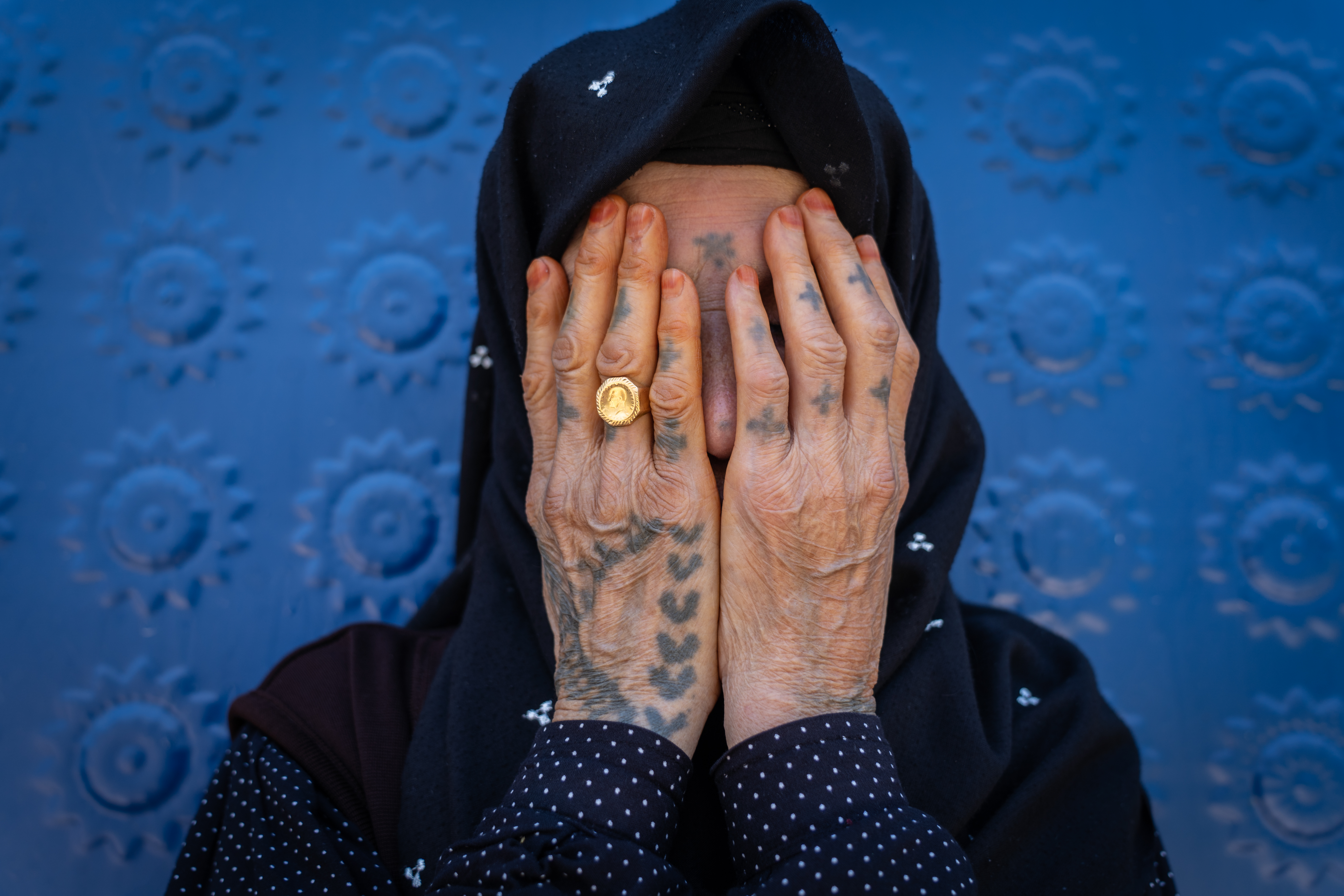 A photo of Fatma Arik, who is in her 70s, with a ladder motif etched across her hands.