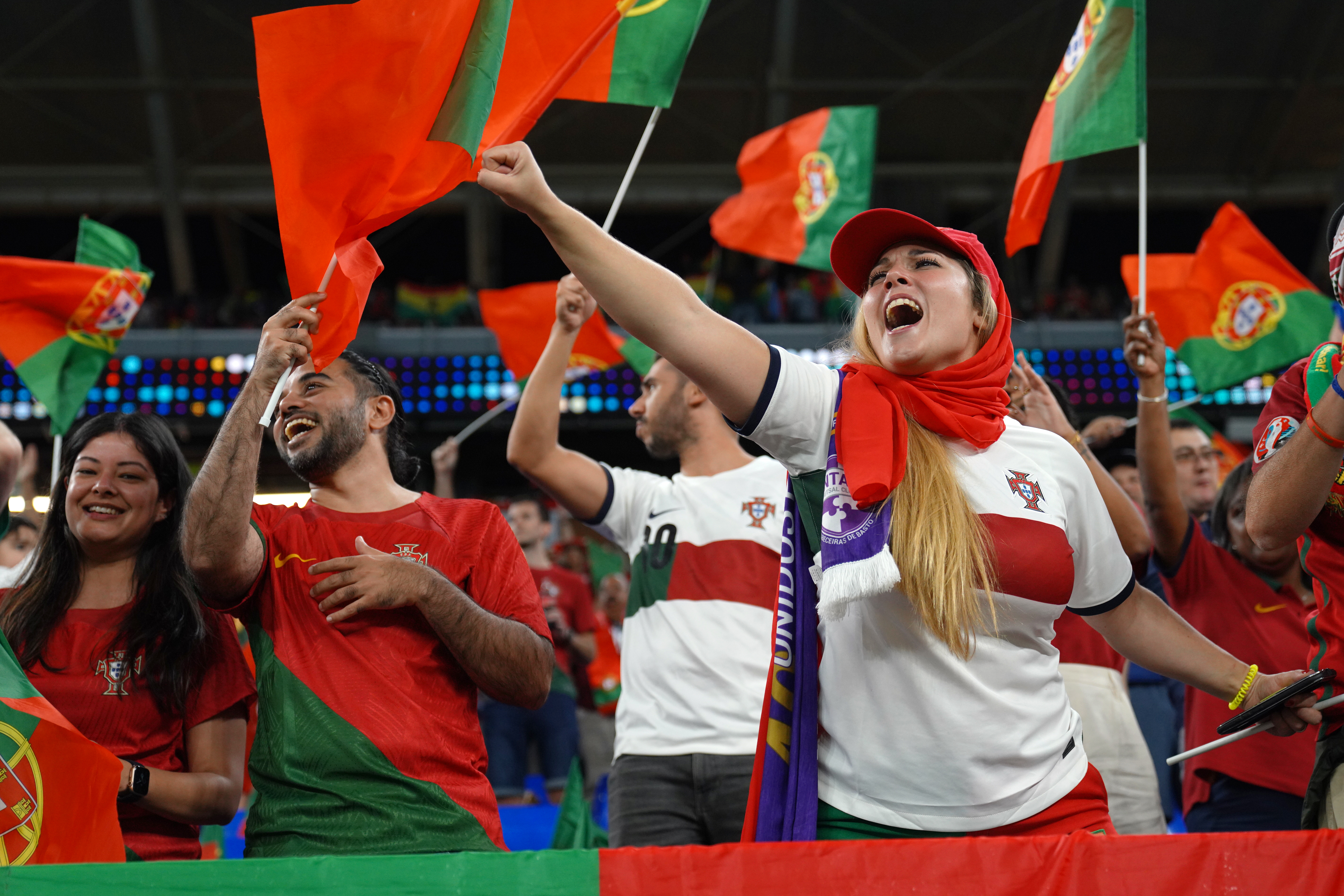 Green and red colours on these fans. Woman yelling, with outstretched fisted hand