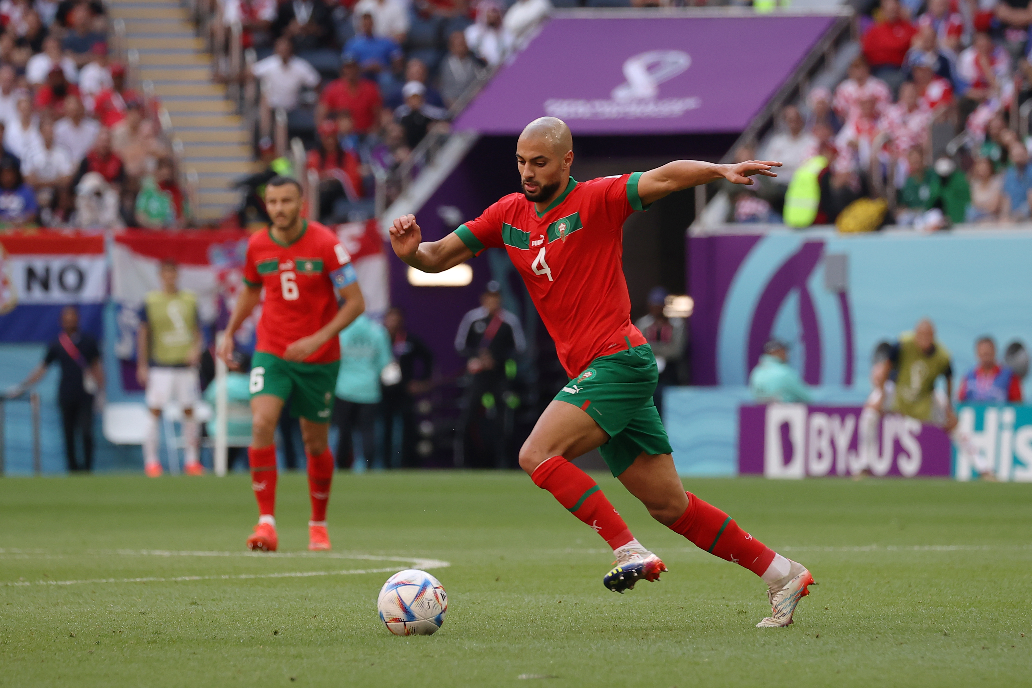 Moroccon player with arms out, in motion, about to kick the ball