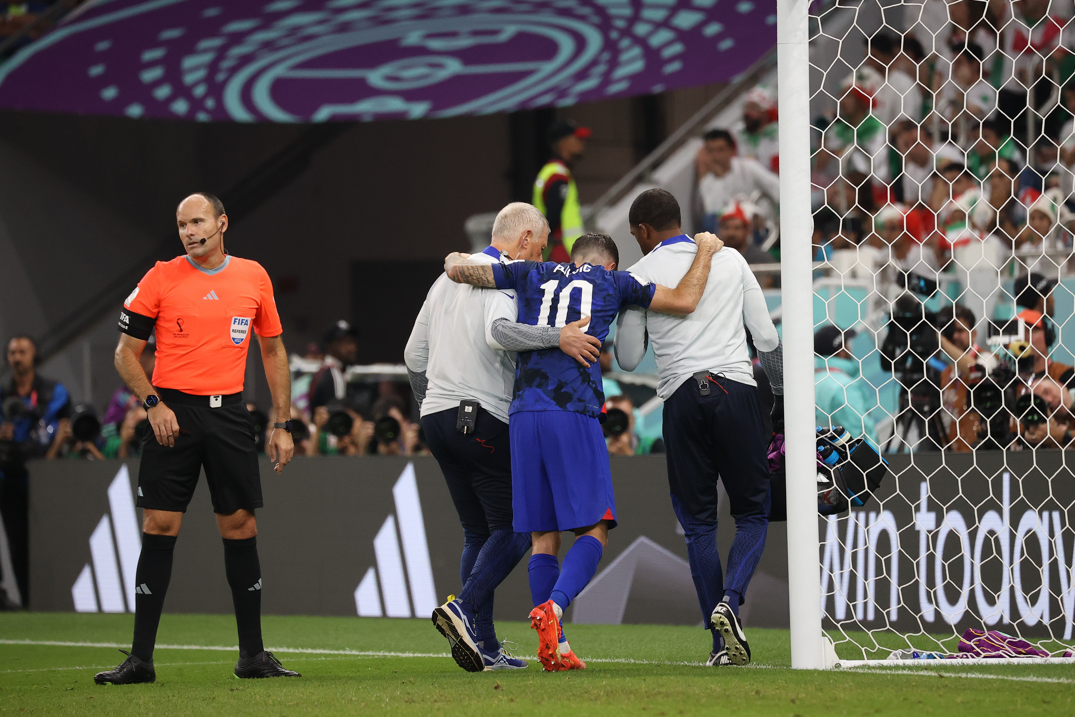 Christian Pulisic being led off the field after the USA's first goal.