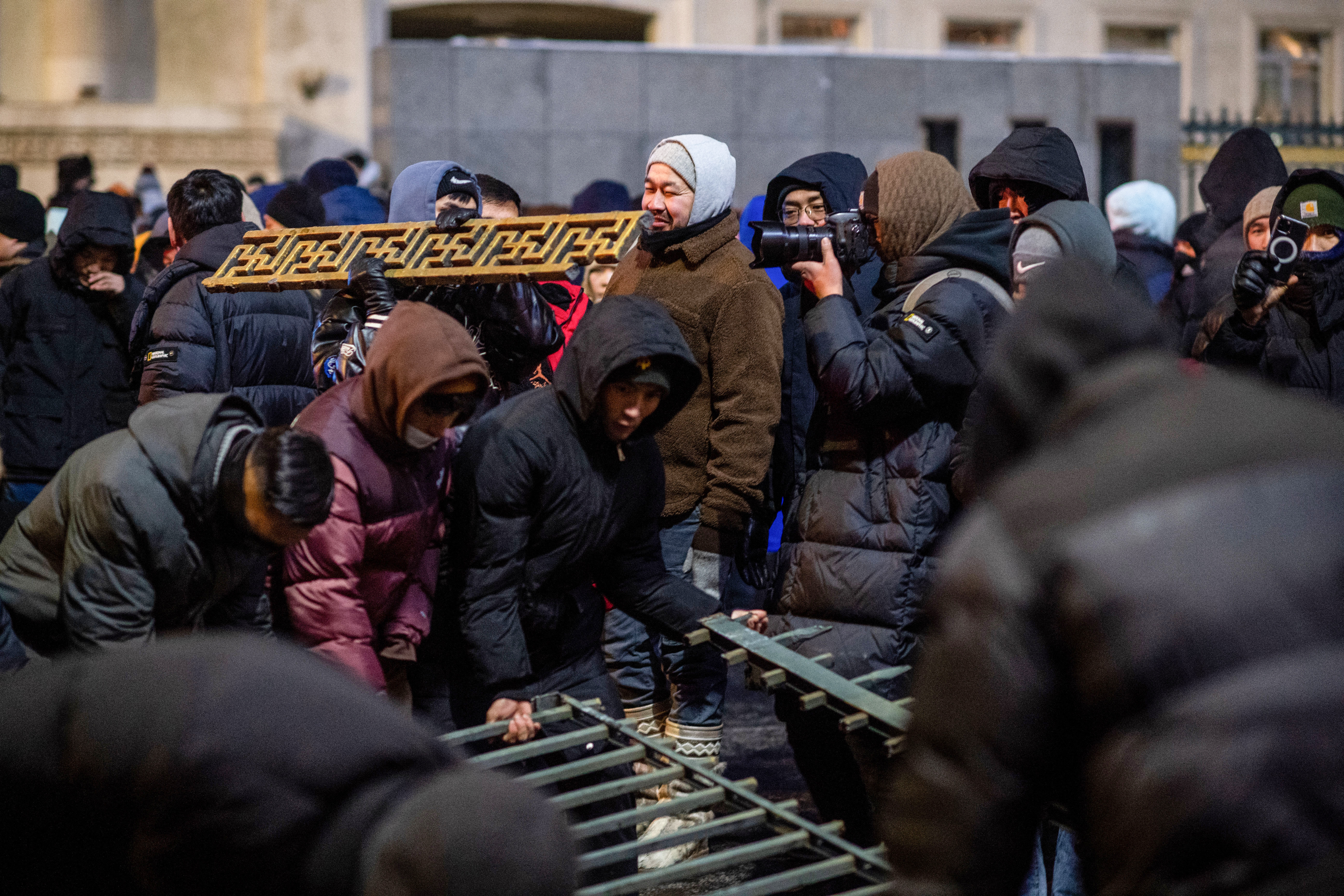 A woman in a thick coat and hat stands among protesters - also wrapped up in warm clothing - in the Mongolian capital.