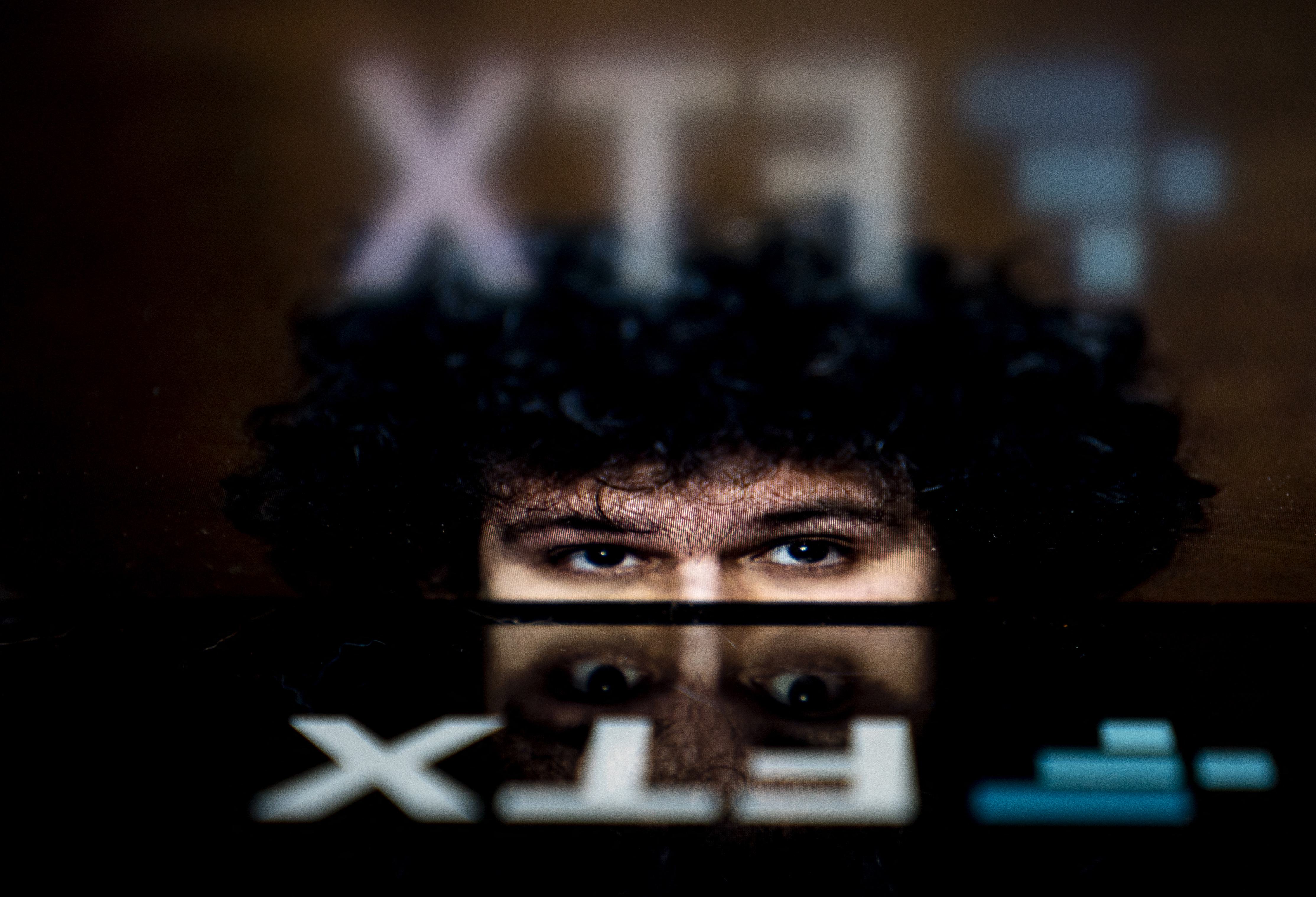 Sam Bankman-Fried's face reflected in the FTX logo.