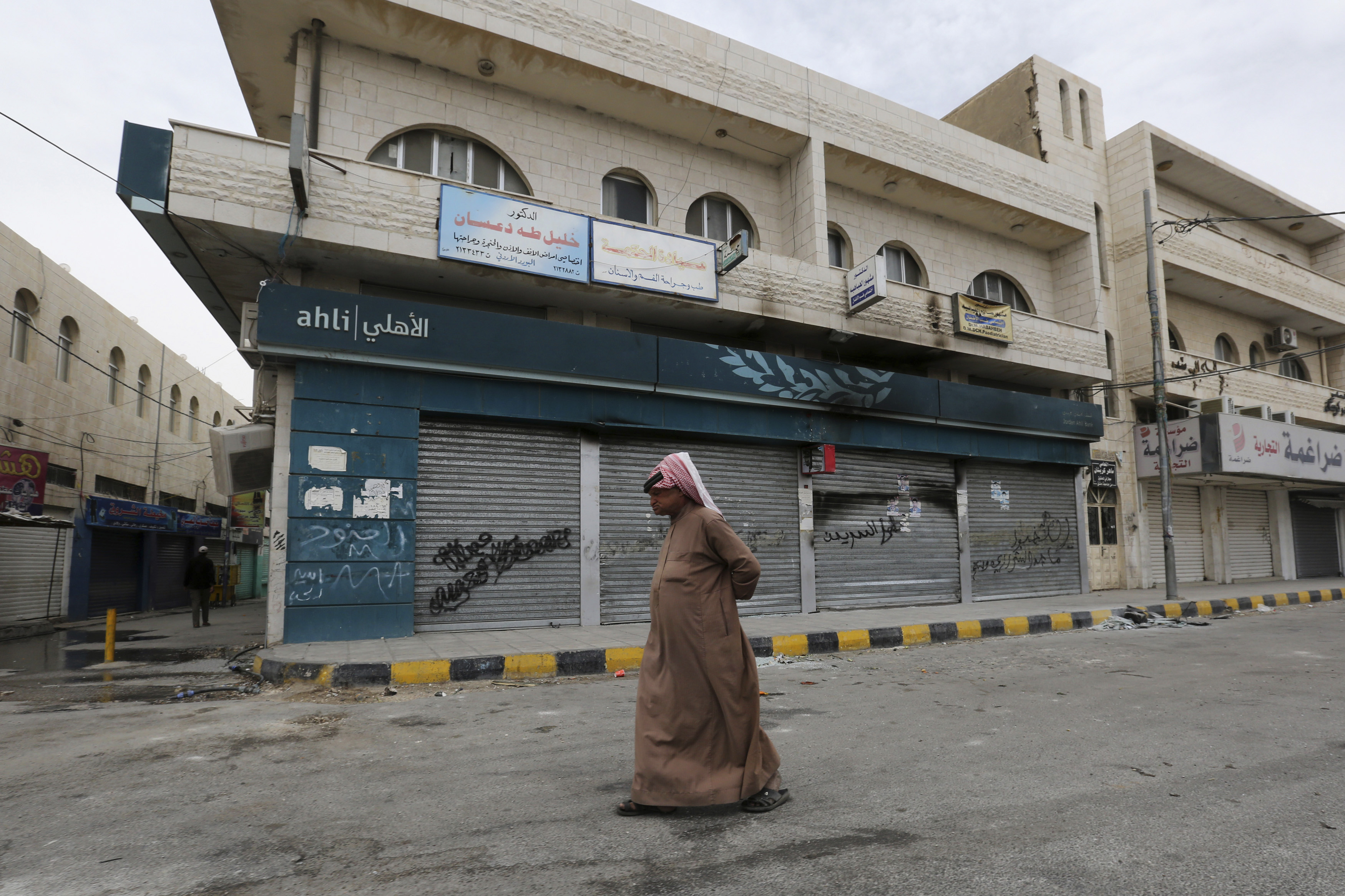 A man walks in front of one of the banks burnt by demonstrators in Maan city